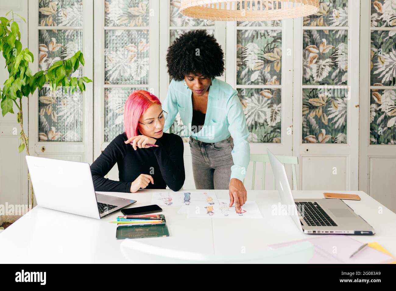 Young multiracial female fashion designers discussing sketches for new ...