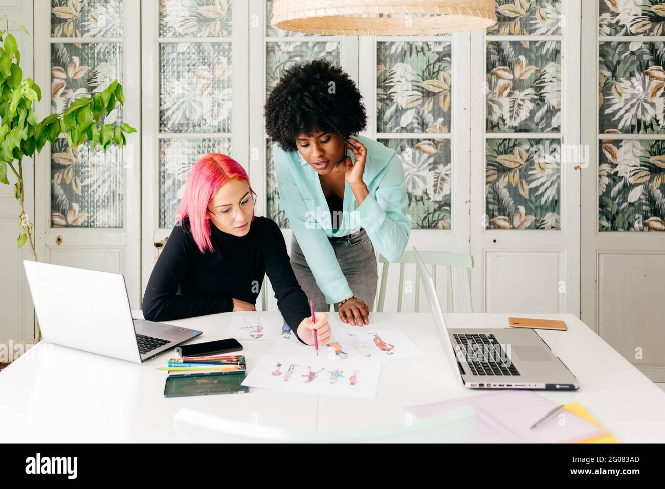 Young multiracial female fashion designers discussing sketches for new ...