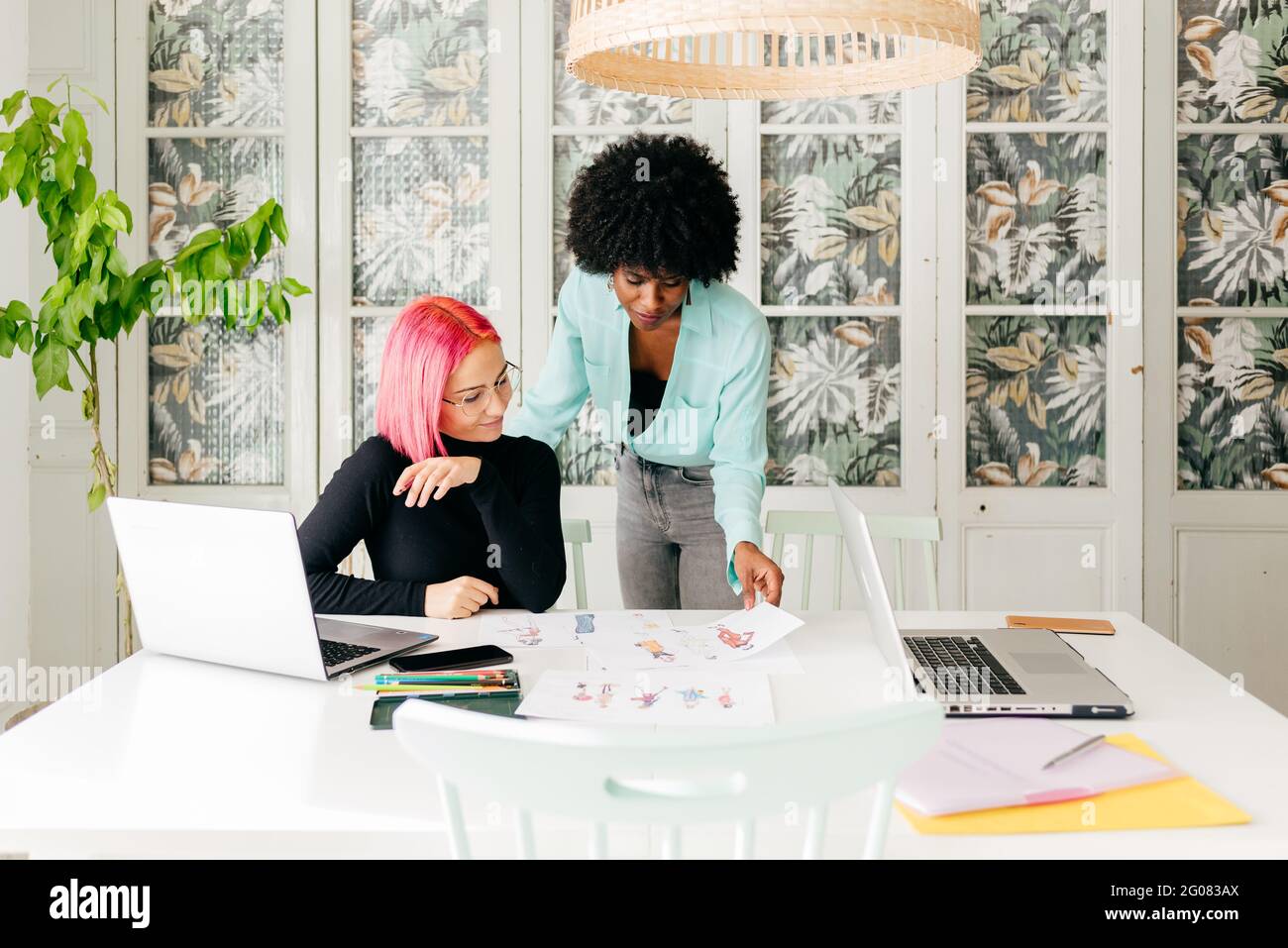 Young multiracial female fashion designers discussing sketches for new ...