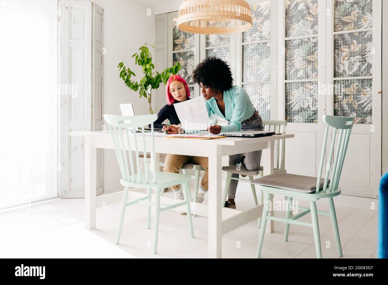 Young multiracial female fashion designers discussing sketches for new ...