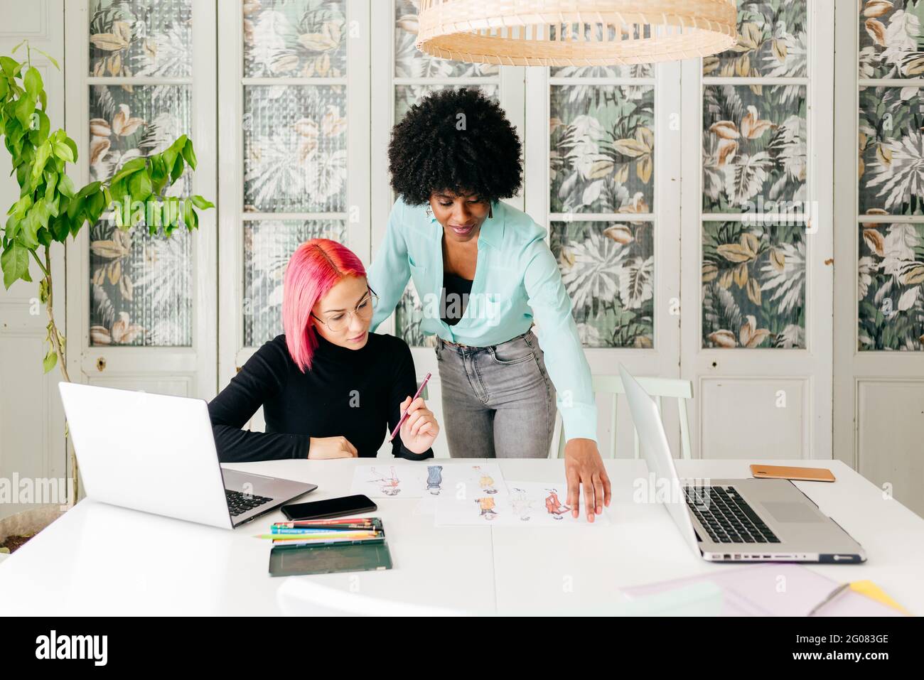 Young multiracial female fashion designers discussing sketches for new ...
