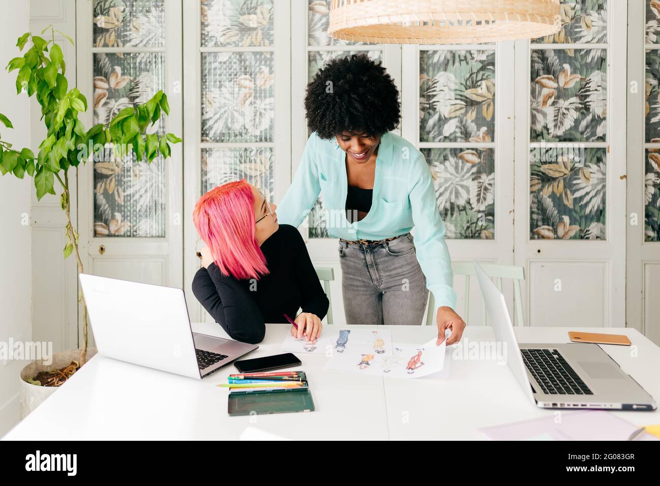 Young multiracial female fashion designers discussing sketches for new ...
