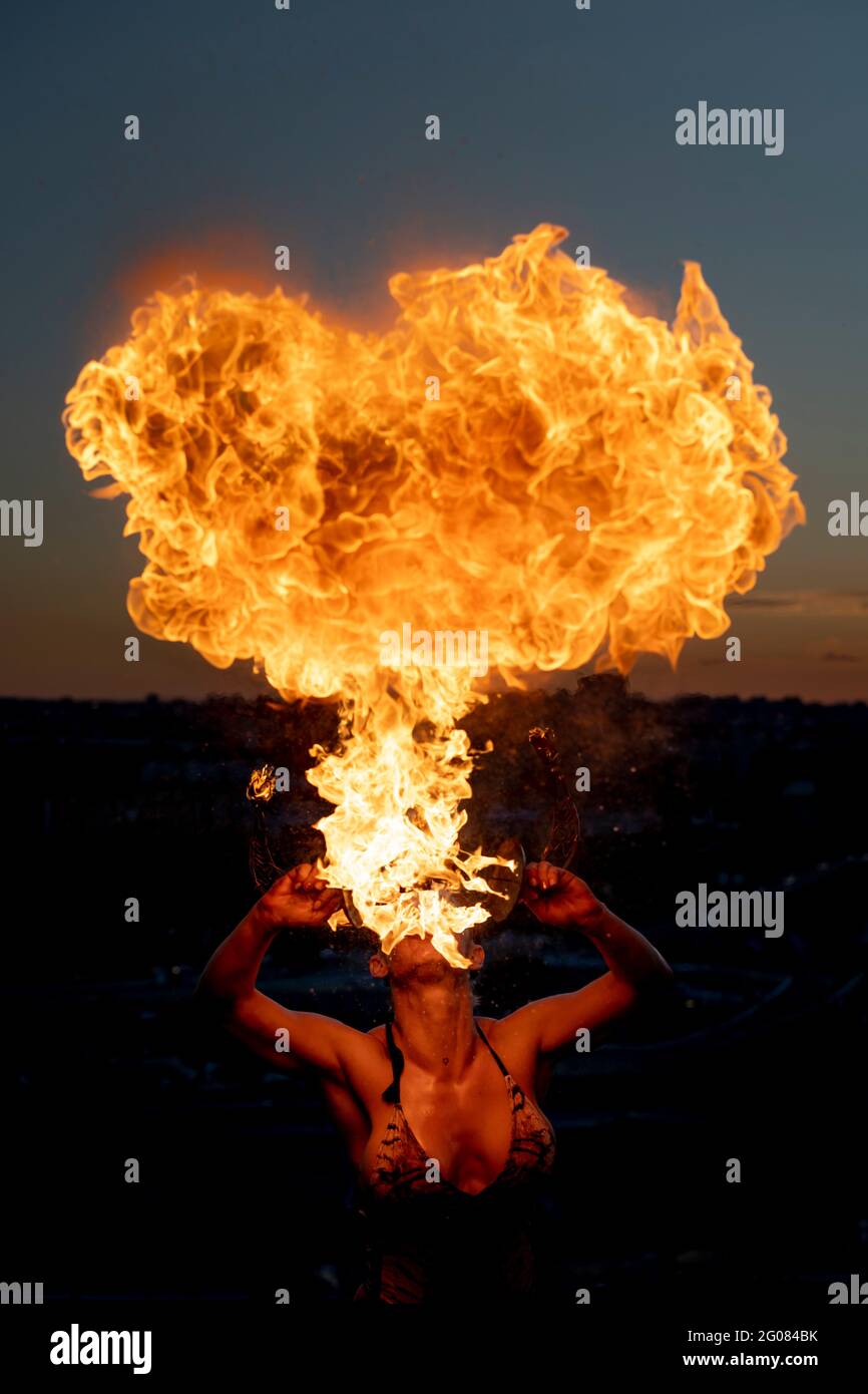 Fire-Eater Woman Performing Spit Fire At Sunset Stock Photo