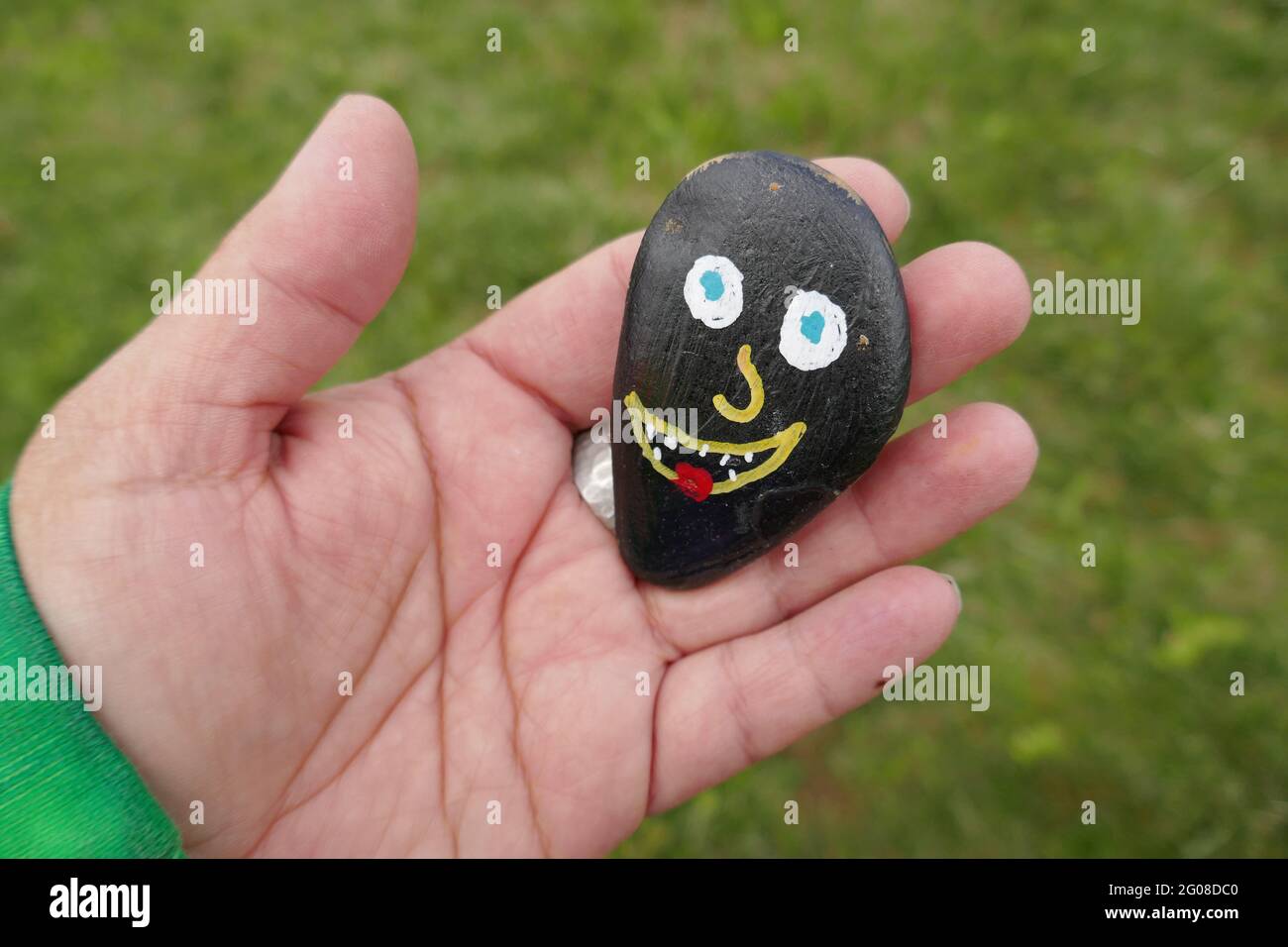 Silly funny face painted on kindness rock held in woman's hand Stock Photo
