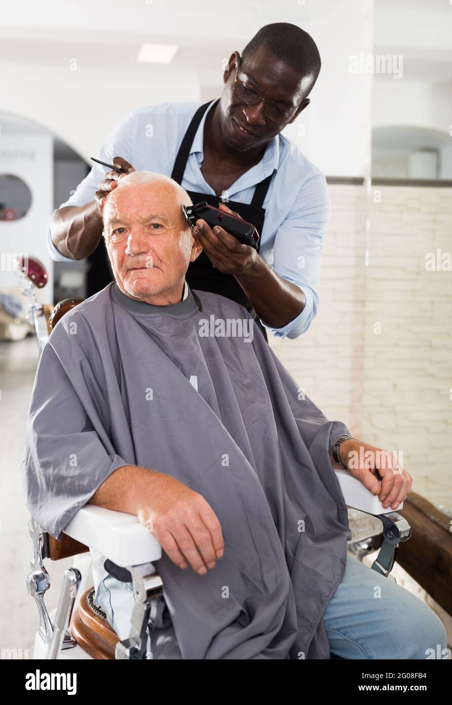 African hairdresser doing styling for grayhaired man Stock Photo Alamy