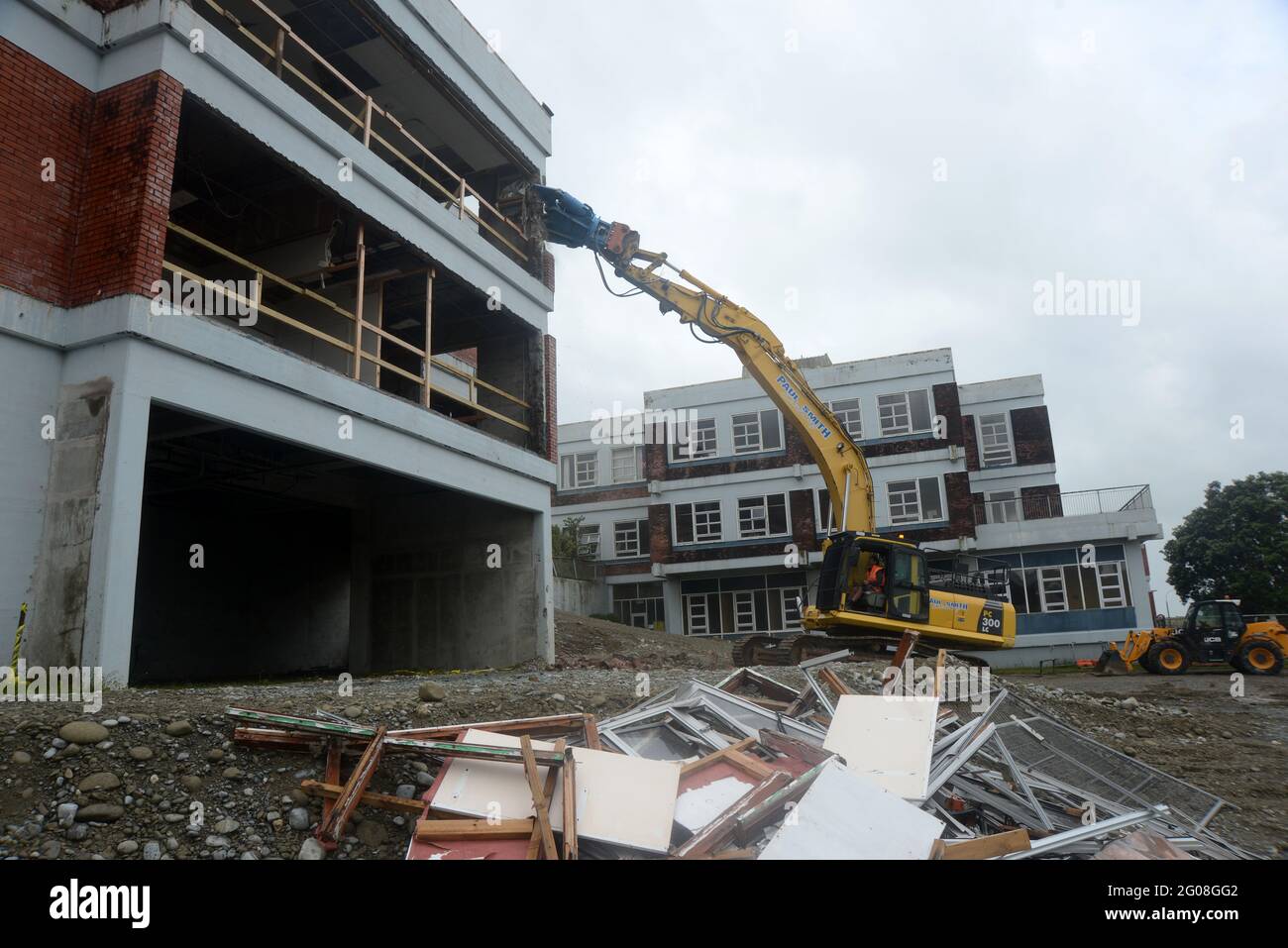 GREYMOUTH, NEW ZEALAND, January 19, 2021: An excavator uses a claw attachment to demolish the old hospital building in Greymouth, New Zealand, January Stock Photo