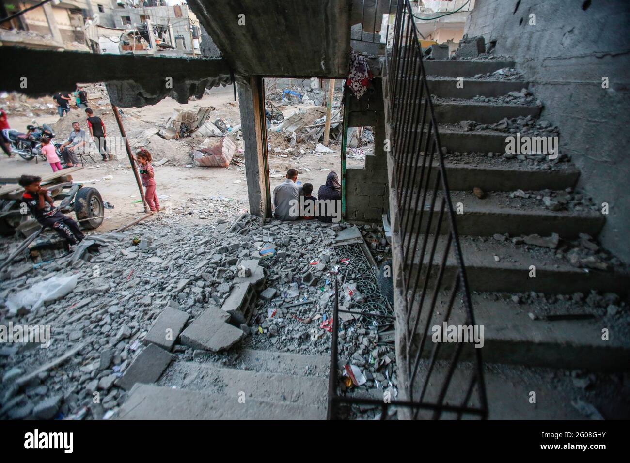 A Palestinian family sits at the door of their destroyed house. The ...