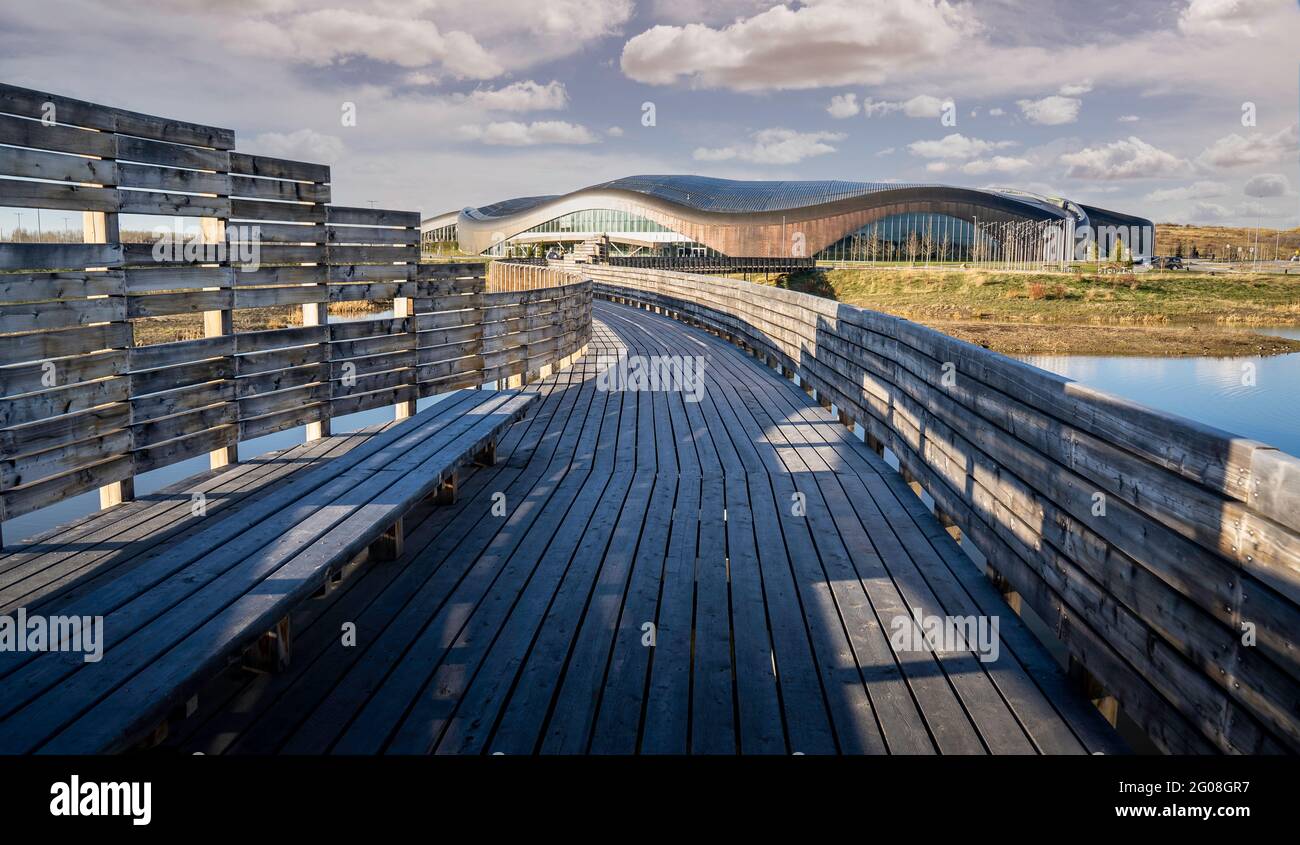 Calgary Alberta Canada, May 12 2021: A wooden boardwalk bridge at the Rocky Ridge YMCA sport facility crosses over a natural habitat area in a Canadia Stock Photo