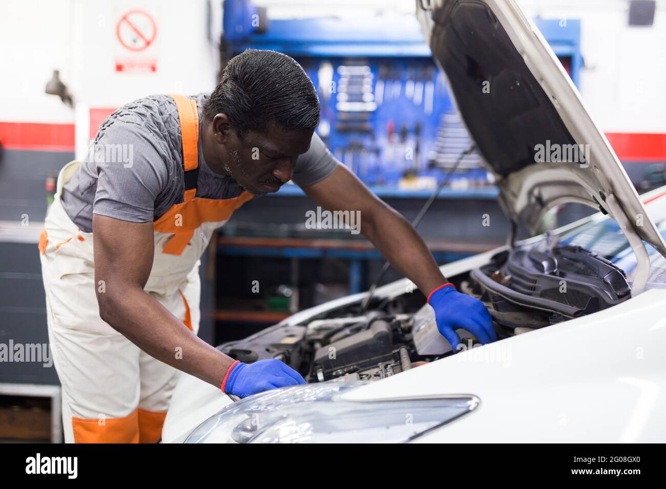 Professional american mechanic man in uniform repairing car engine