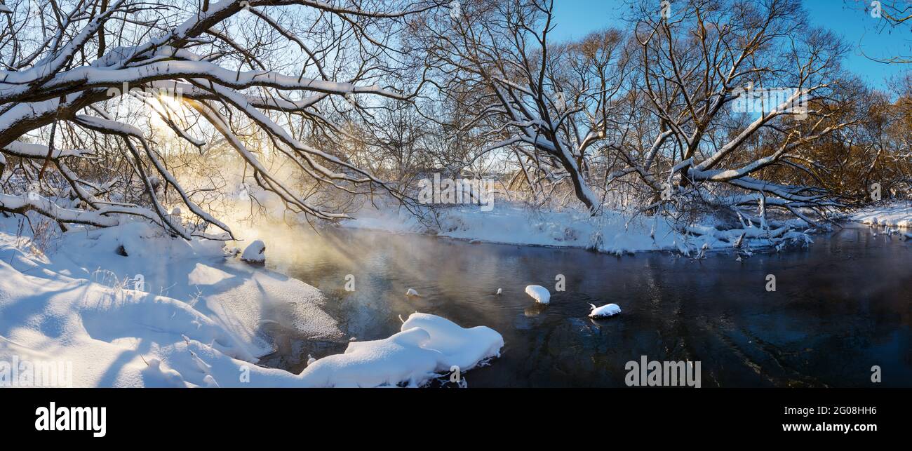 Frosty winter landscape with forest river and foggy sunlight during sunny january morning Stock Photo