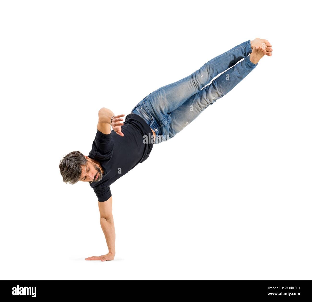 Fit athletic casual barefoot man doing a hip hop balancing pose on one hand isolated on a white background with copyspace Stock Photo