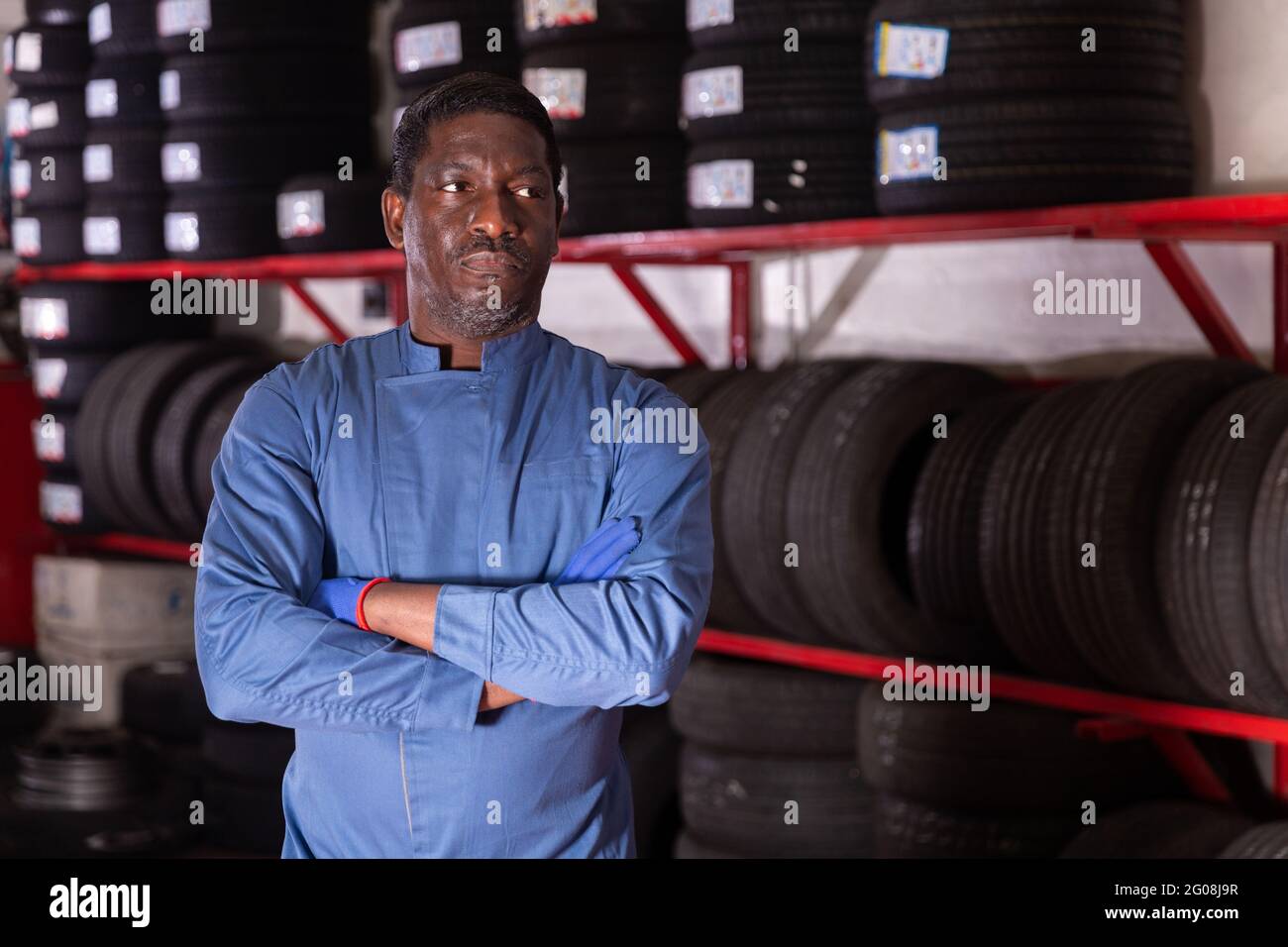 Portrait of serious auto mechanic in front of car tires Stock Photo - Alamy