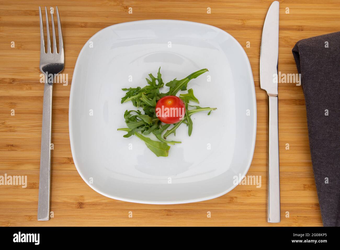 top view of a small portion salad on a white plate with cutlery Stock Photo