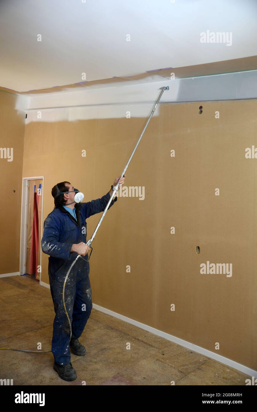 a tradesman using airless spray equipment to paint a primer coat on the