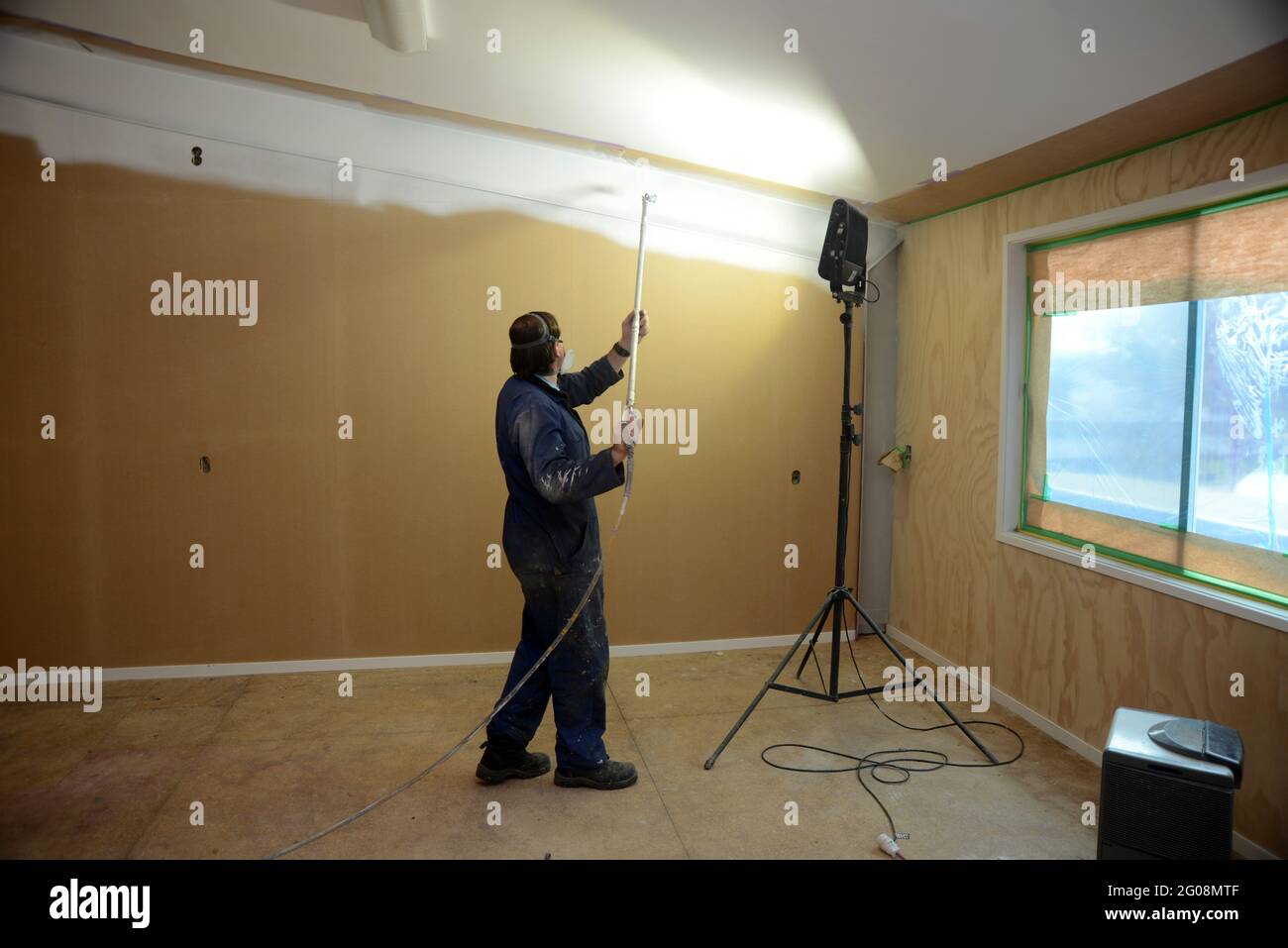 a tradesman using airless spray equipment to paint a primer coat on the ...
