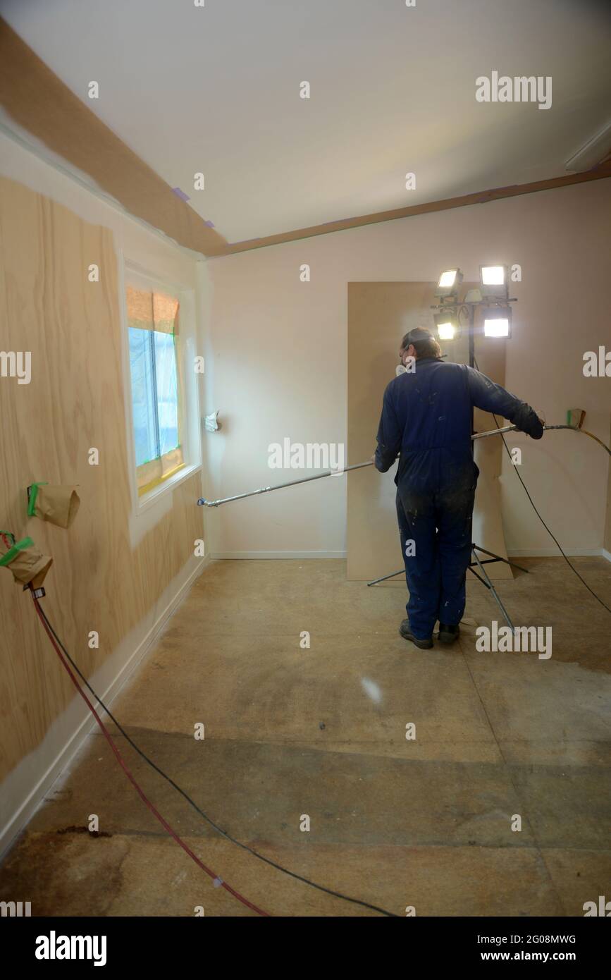 a tradesman using airless spray equipment to paint a primer coat on the ...