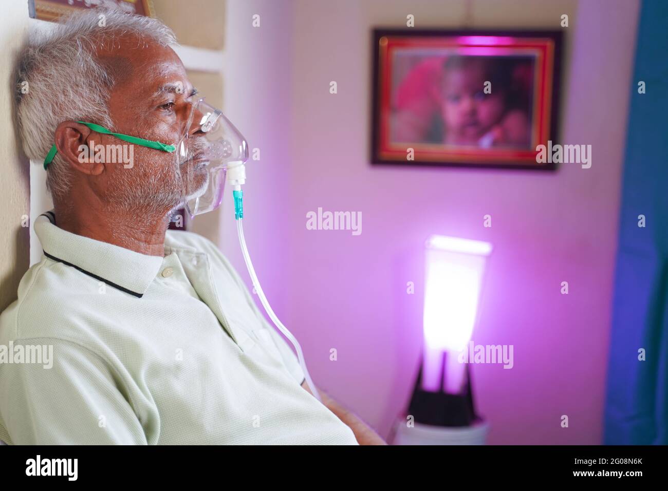 Medium Close up shot of elderly man on oxygen concentrator at home due to availability of beds in hospital for coronavirus covid-19 infection people - Stock Photo