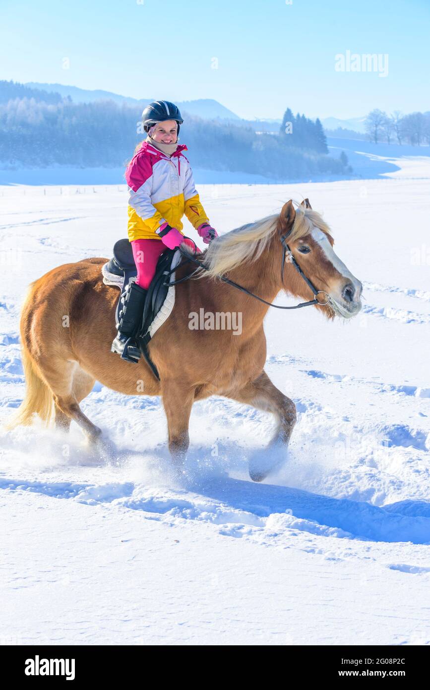 Young girl during ride-out with her horse into the snowy nature in Allgäu Stock Photo