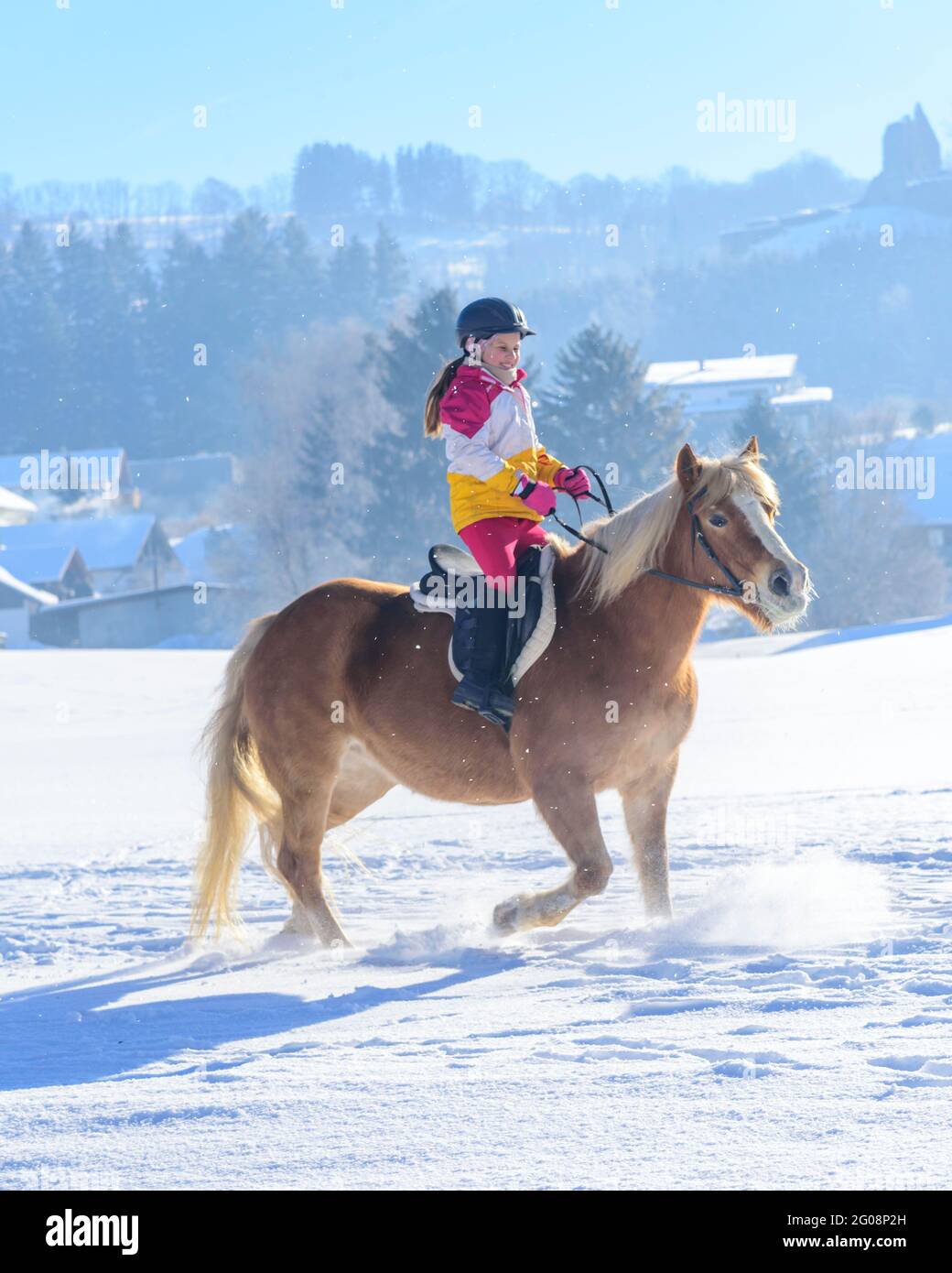 Young girl during ride-out with her horse into the snowy nature in Allgäu Stock Photo