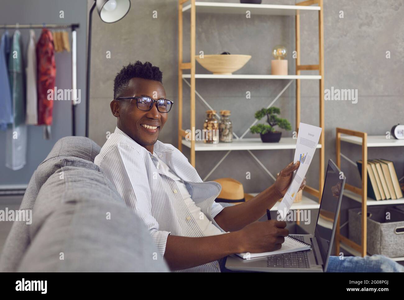 Happy successful black businessman working on couch in his comfortable home office Stock Photo