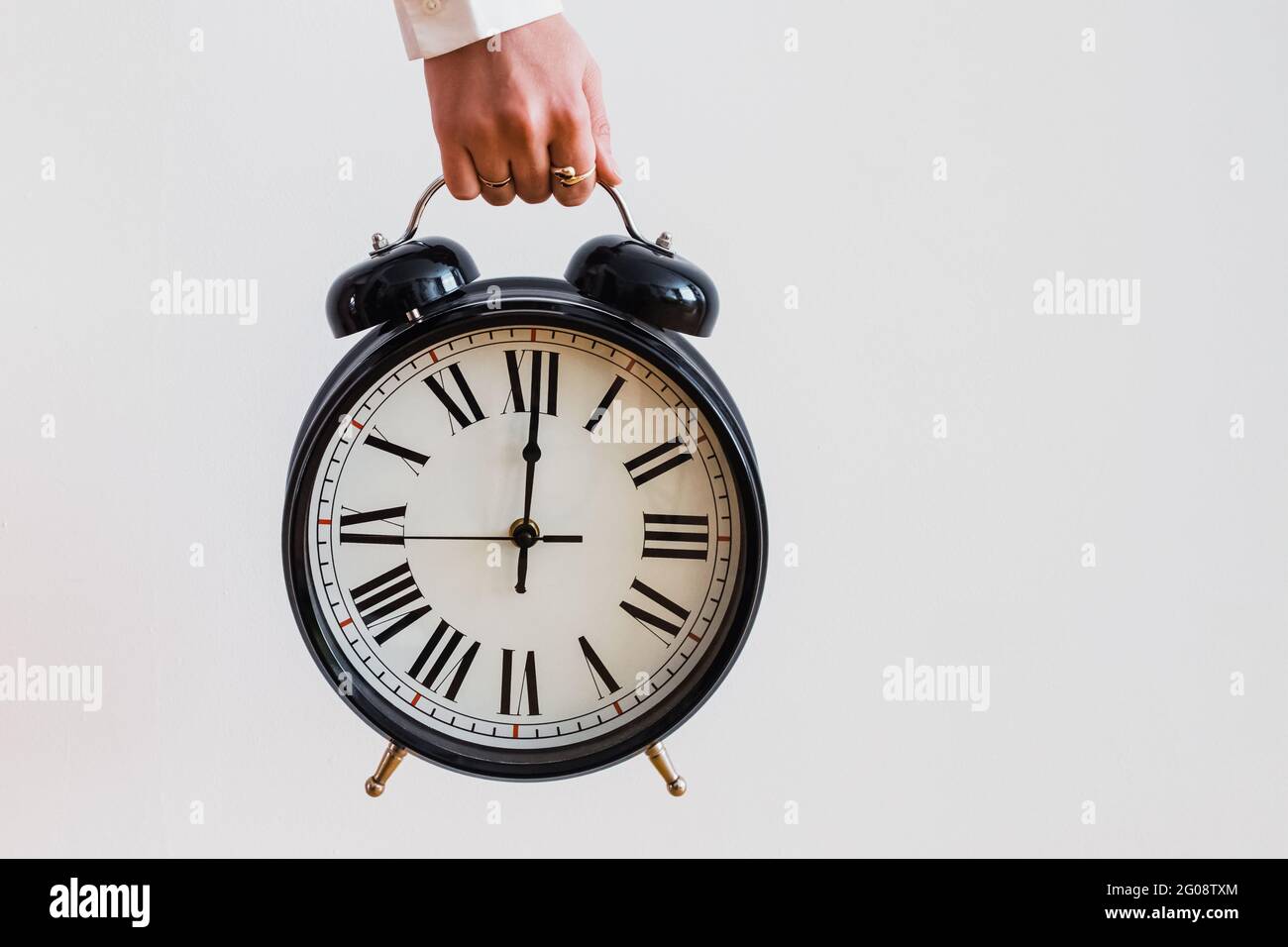 Female hand holding a big vintage alarm clock Stock Photo