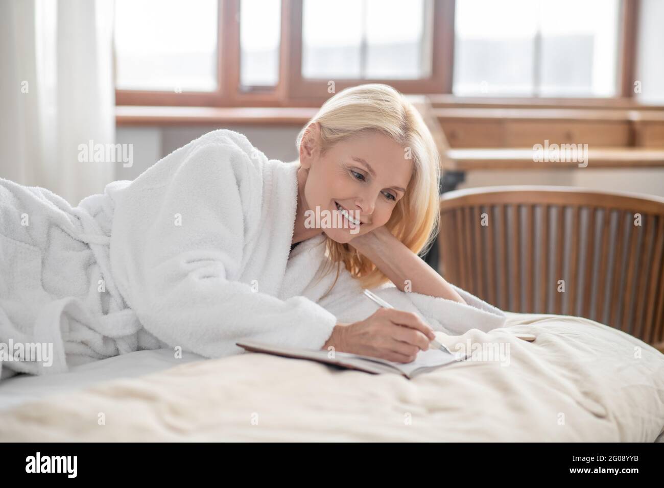 A cute woman lying on the bed and making notes Stock Photo