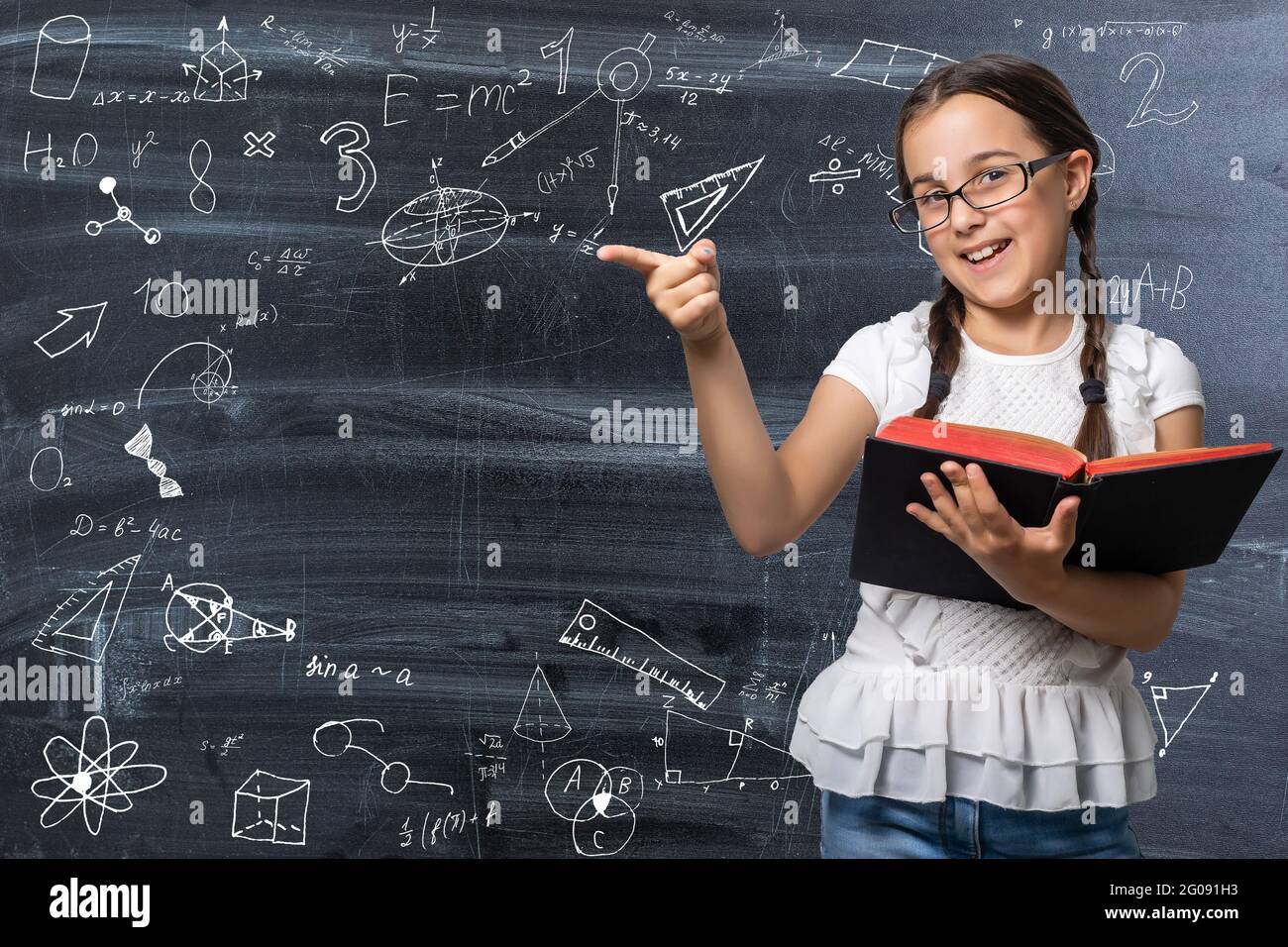Lovely little girl standing and holding book over white background ...
