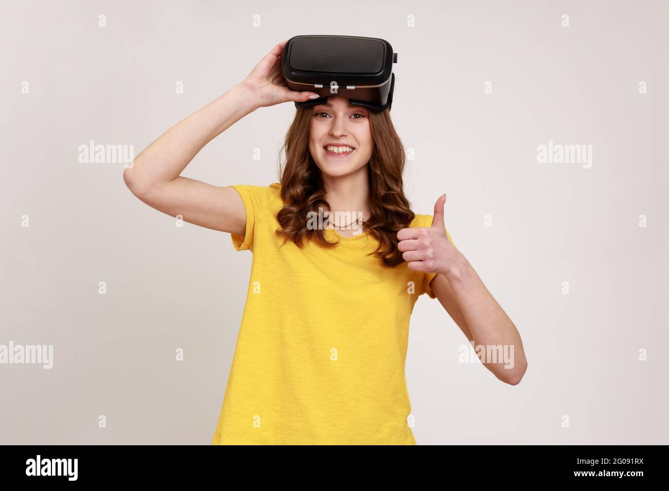 I like VR technology! Satisfied girl with virtual reality glasses  expressing happiness after playing game simulator, standing with thumbs up.  Indoor s Stock Photo - Alamy