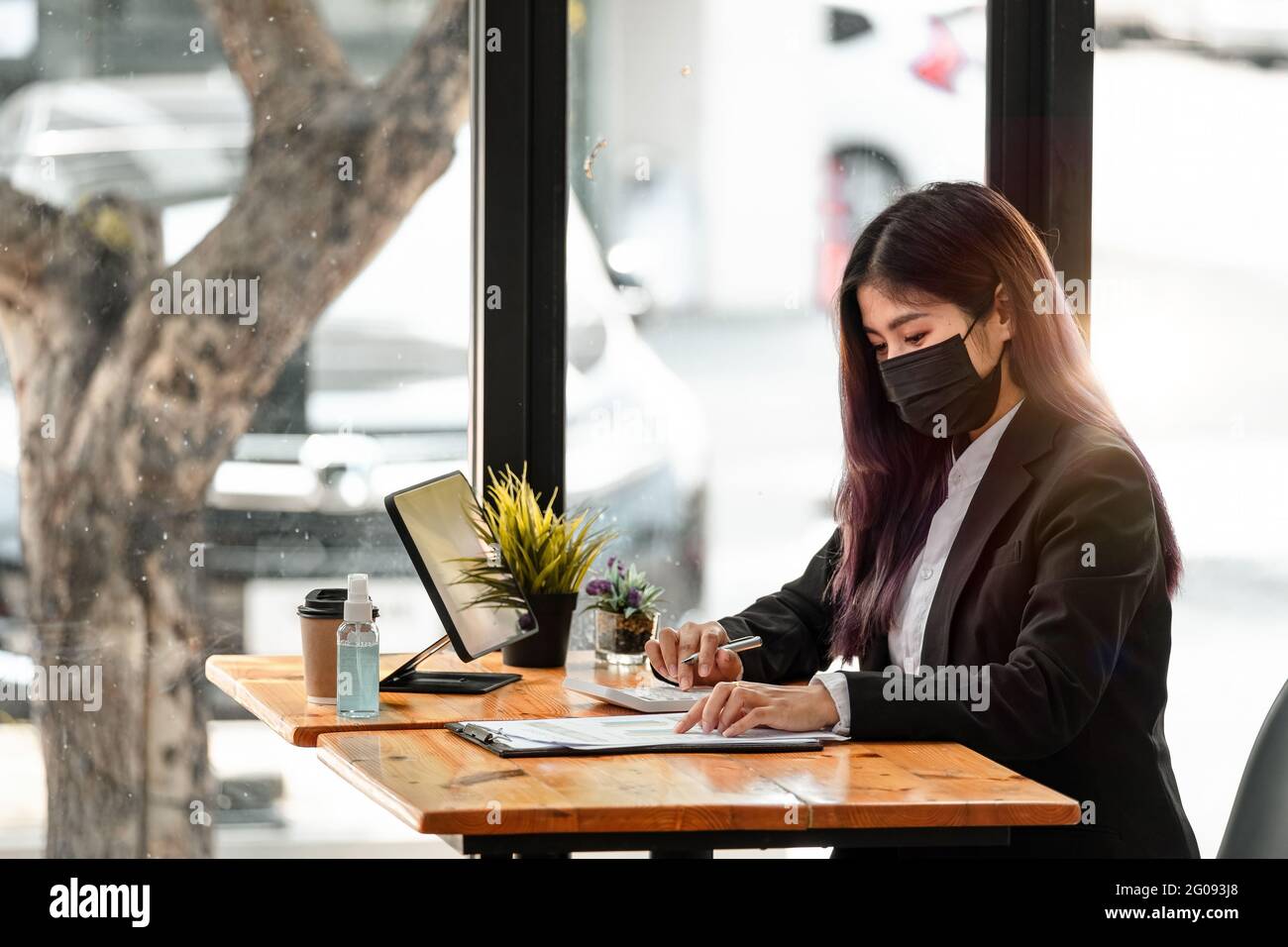 Side view of asian businesswoman wearing face mask while working on a computer in the office. hygiene and safety concept. Stock Photo