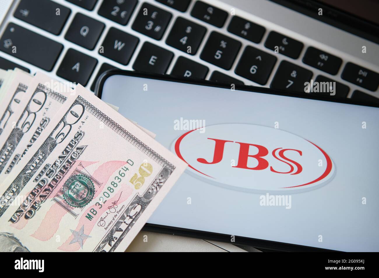 JBS meat producer logo seen on the smartphone screen with blurred money