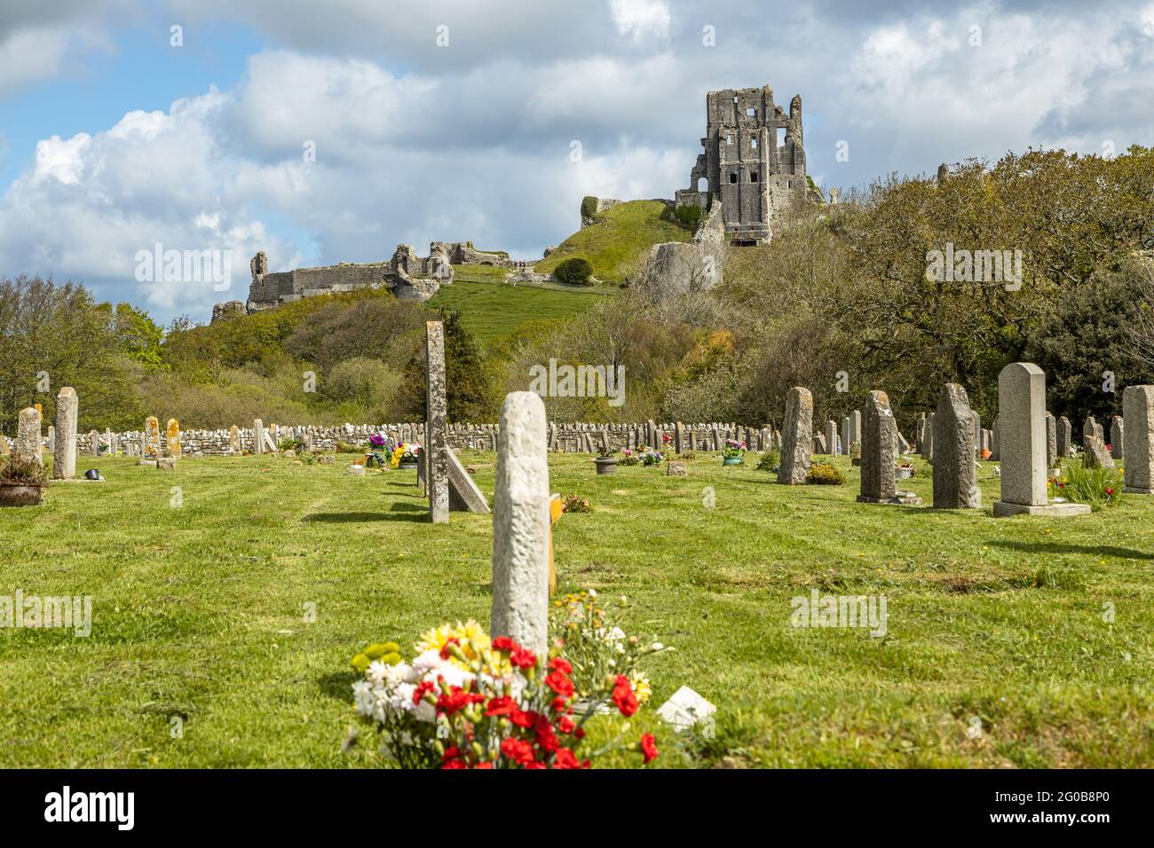 Corfe Castle a Saxon stronghold nestling in the picturesque landscapes of the Purbeck hills overlooks the village graveyard , Dorset England UK Stock Photo