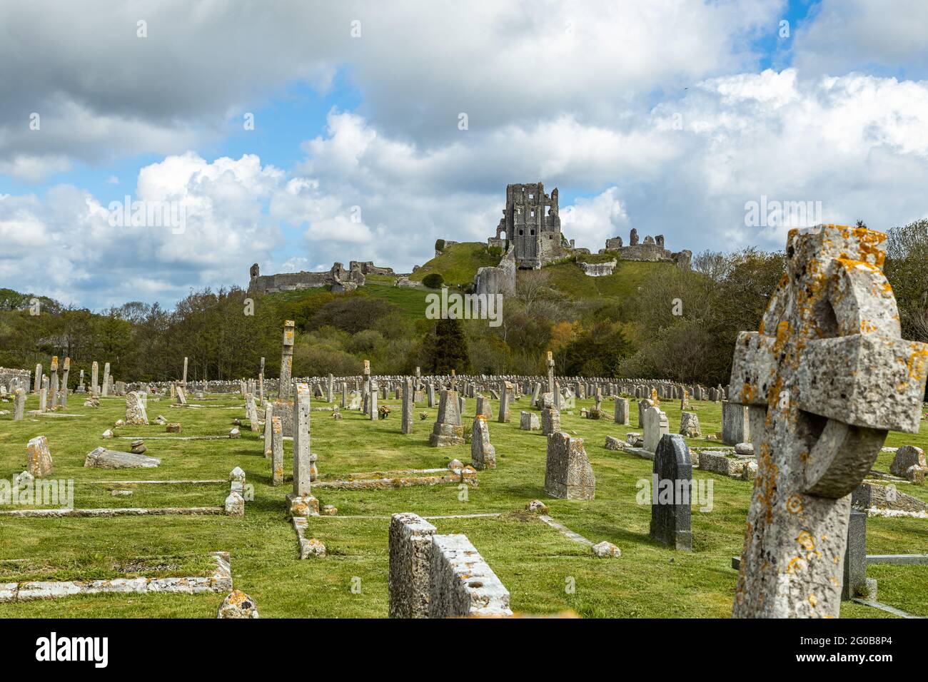 Corfe Castle a Saxon stronghold nestling in the picturesque landscapes of the Purbeck hills overlooks the village graveyard , Dorset England UK Stock Photo