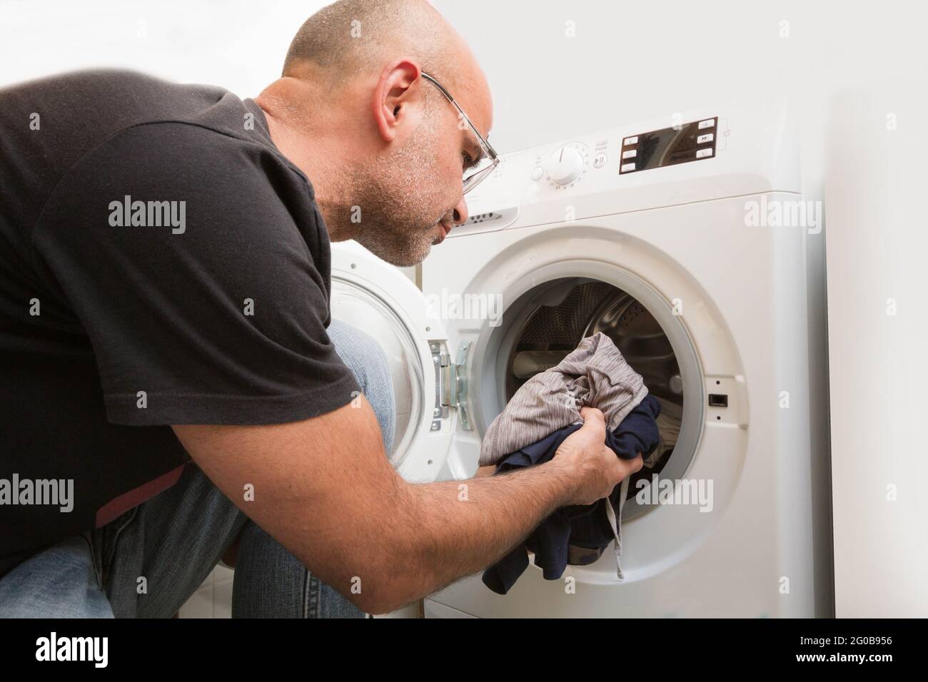 Male loading the washing machine with dirty clothes Stock Photo