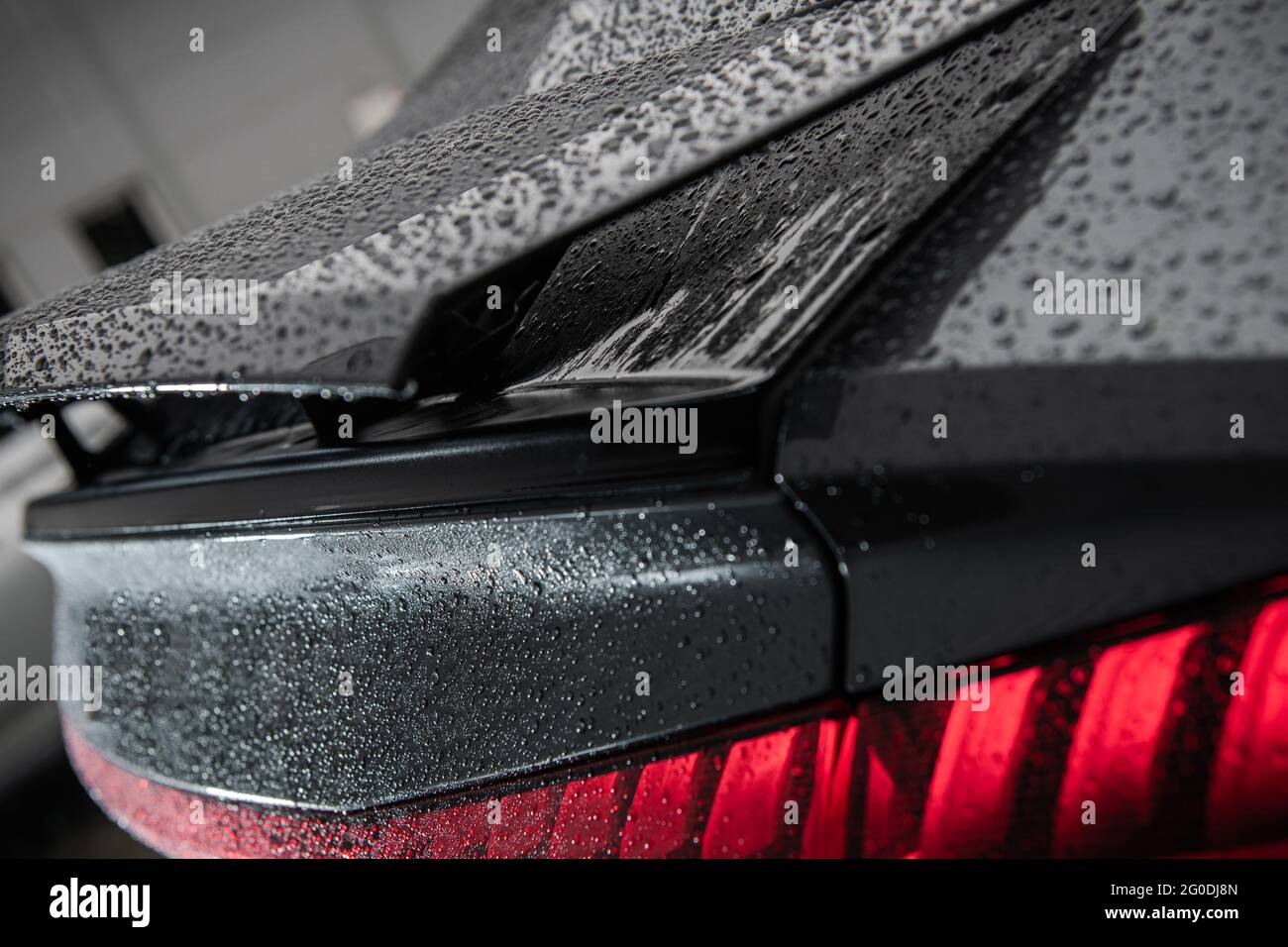 Automotive Theme. Detailed Modern Car Washing. Luxury Vehicle Spoiler and Tail Lights Covered by Water Drops Right After Washing Close Up Stock Photo