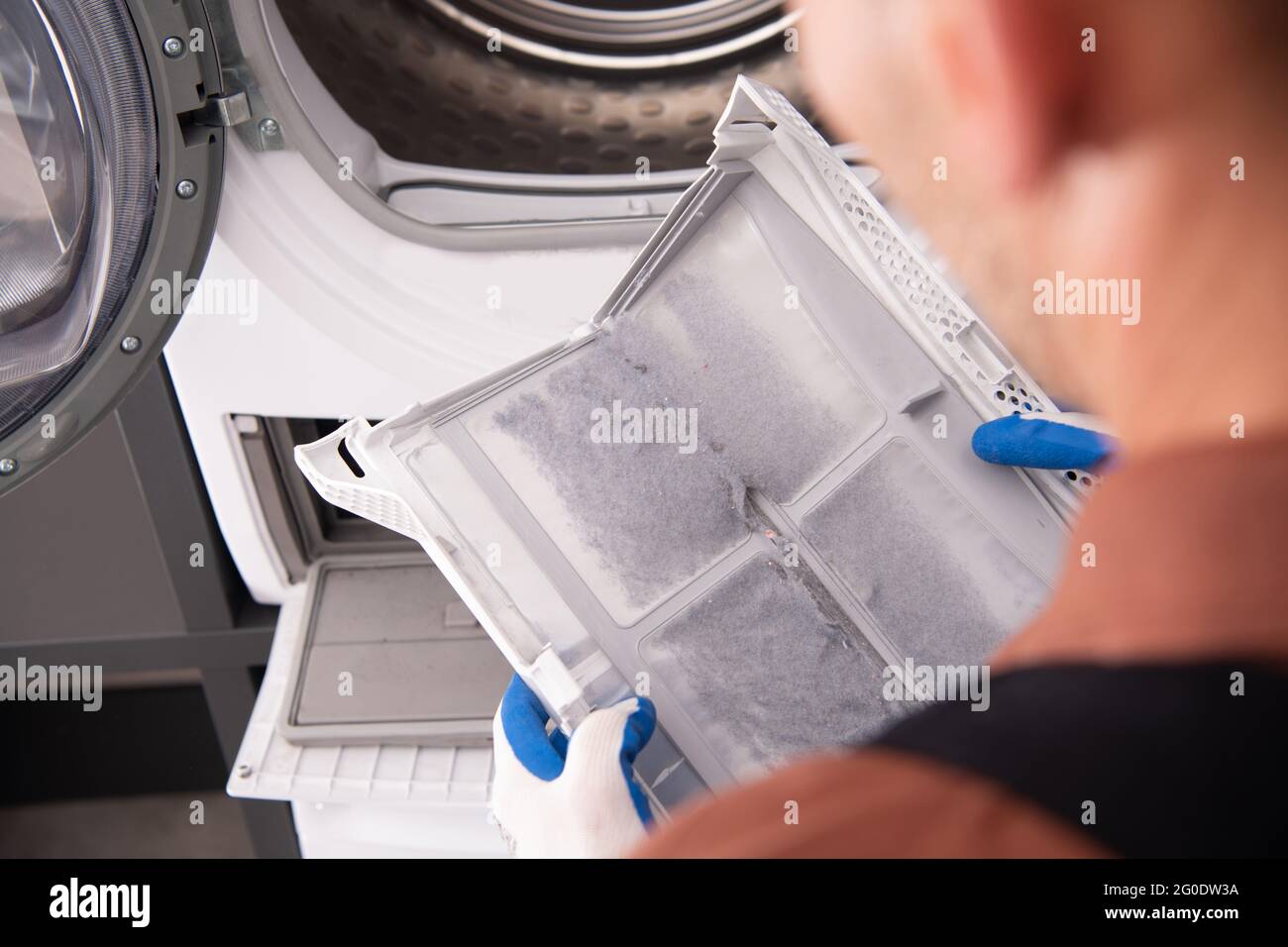 Washing and Dryer Machine Filter Covered by Dirt. Filter Cleaning Performed by Home Appliances Technician. Stock Photo