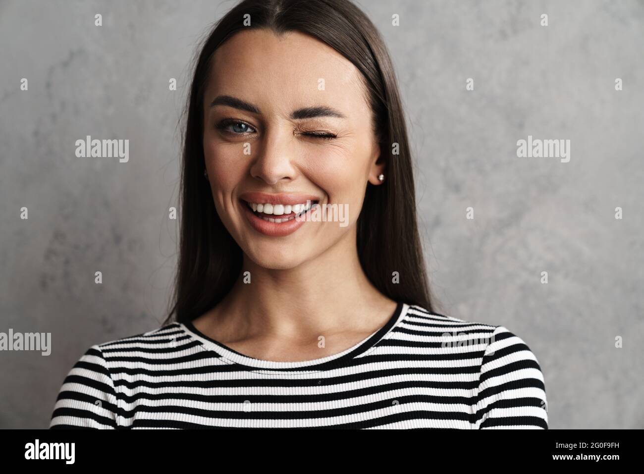 Close Up Of A Beautiful Young Smiling Brunette Woman With Long Hair Isolated Over Gray 