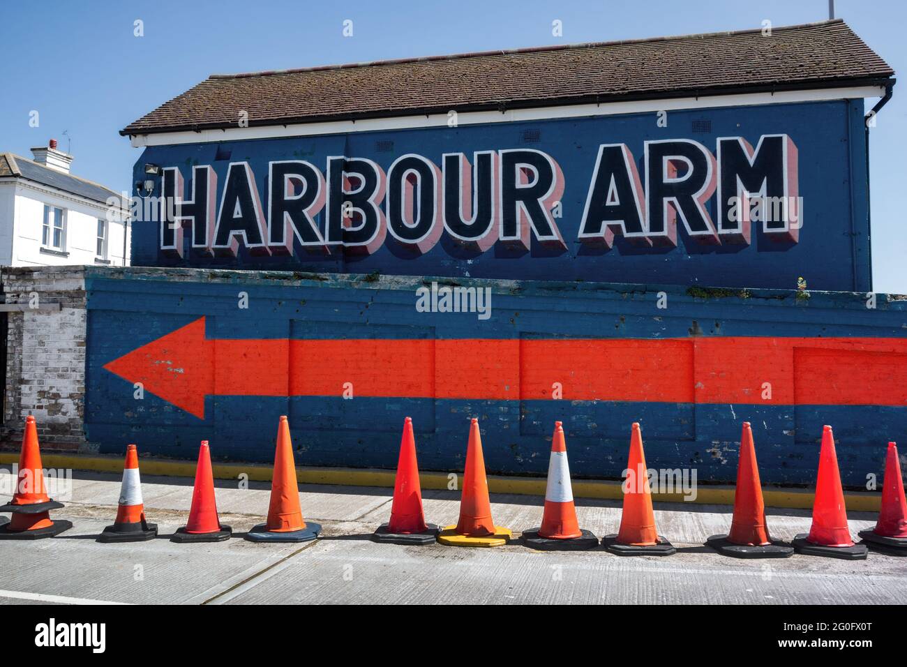 Harbour Arm sign showing a big orange arrow on a bright blue wall, Folkestone Harbour Stock Photo