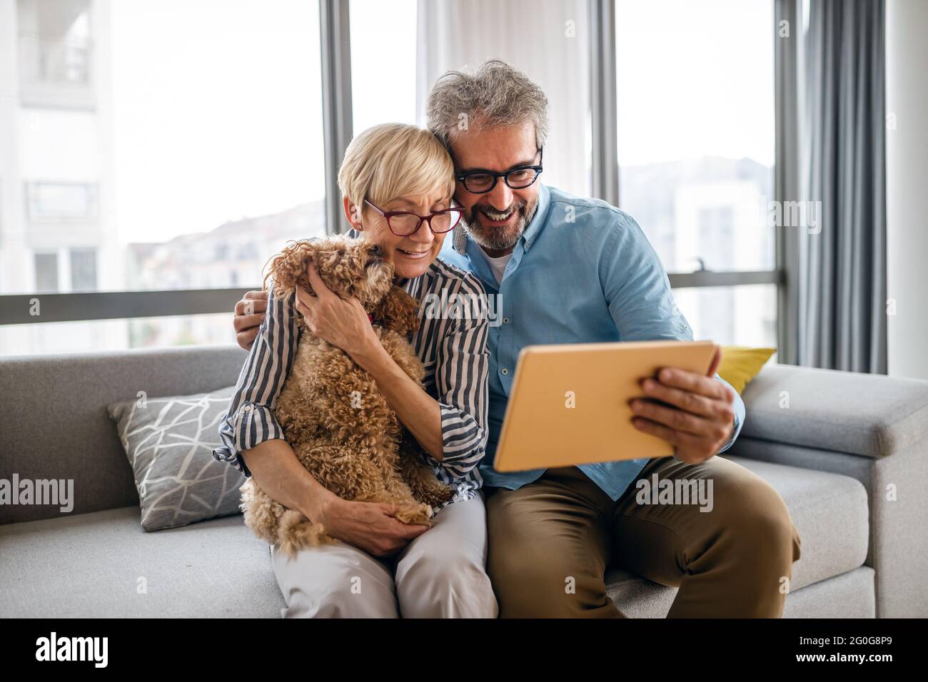 Lovely smiling mature couple having fun while using tablet at home Stock Photo