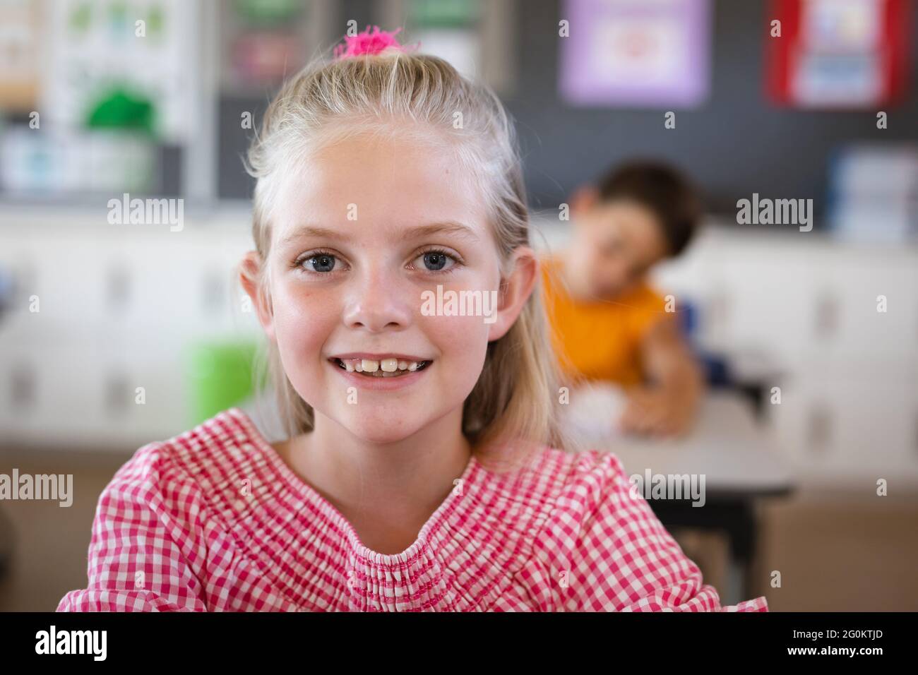 Portrait of caucasian girl smiling while sitting on her desk in the ...