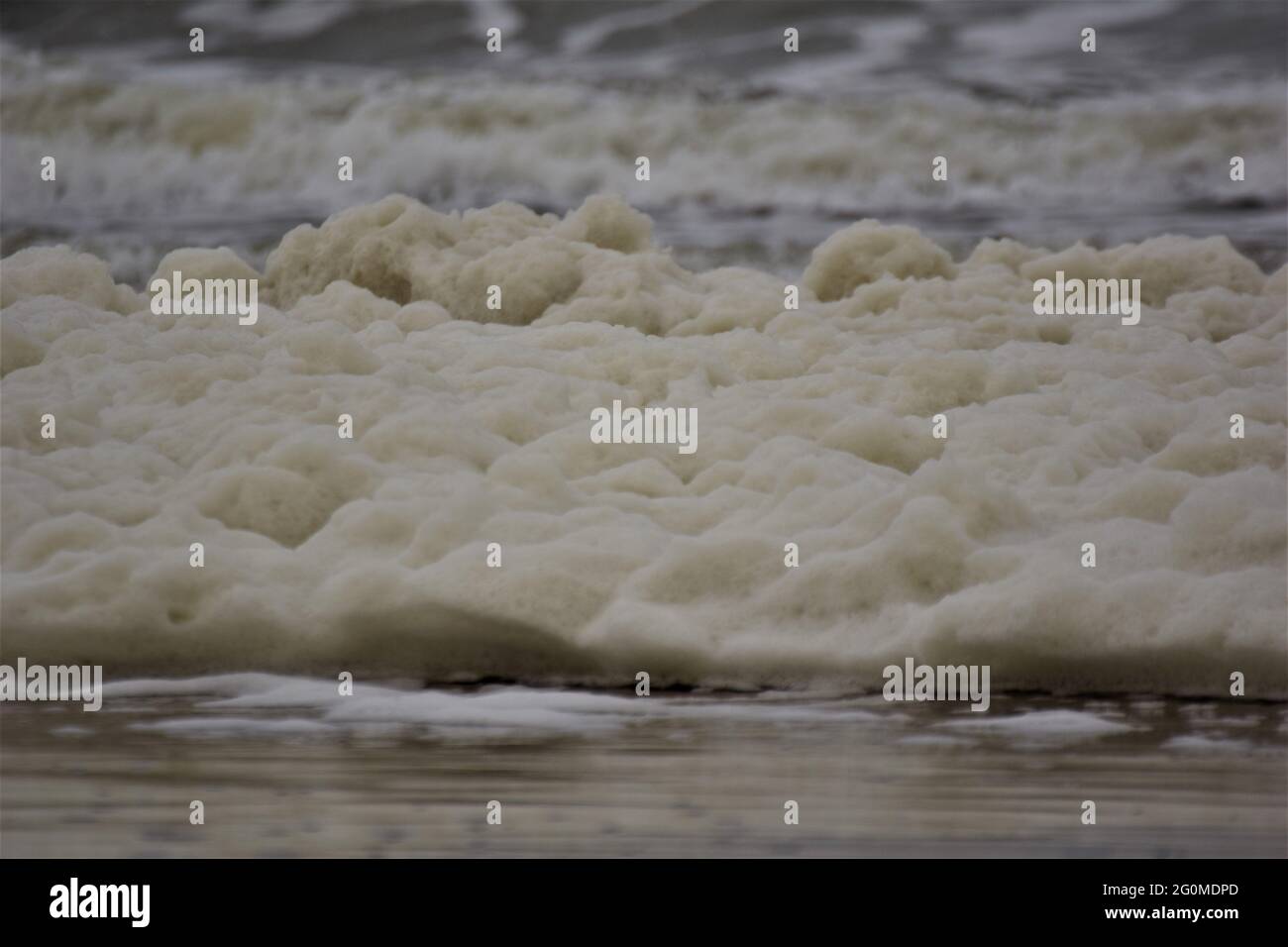 Waves and sea foam on a beach of the North Sea on a cloudy day Stock Photo