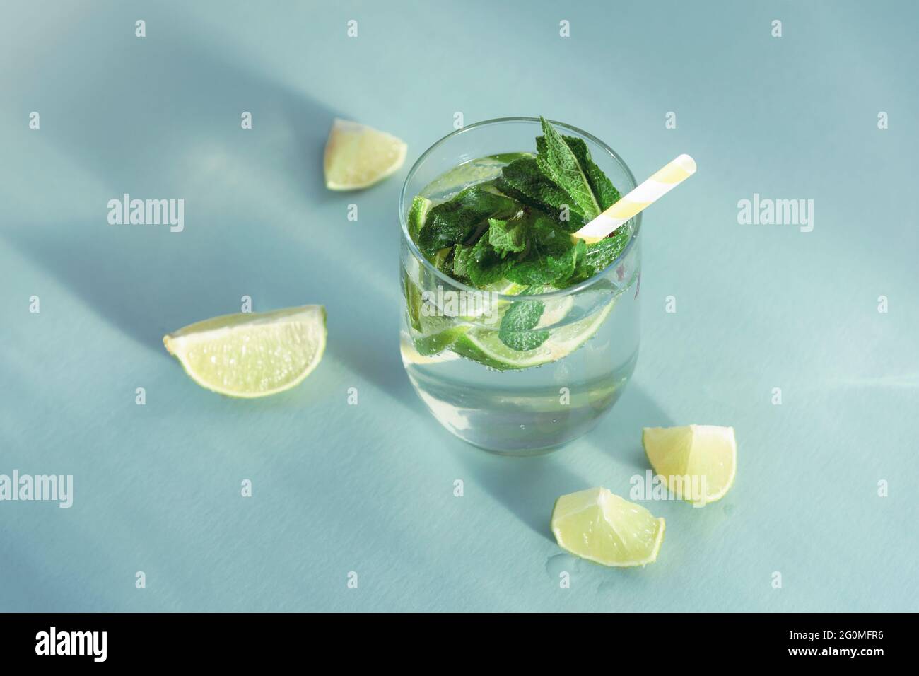 Mojito drink with straw on blue table. Cold refreshing drink with mint and lemon slices, top view. Stock Photo