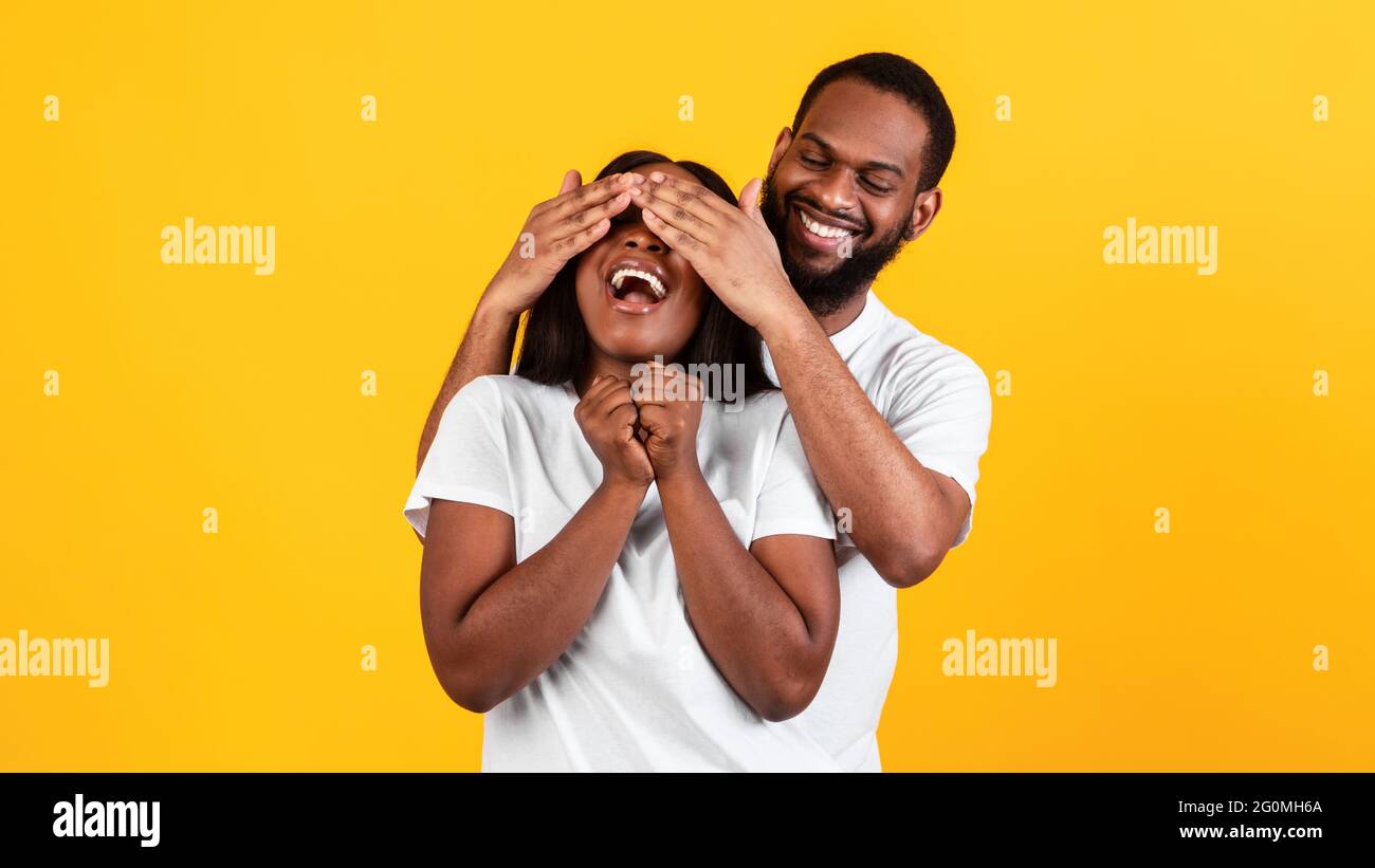 Black man making surprise for his woman, covering eyes Stock Photo