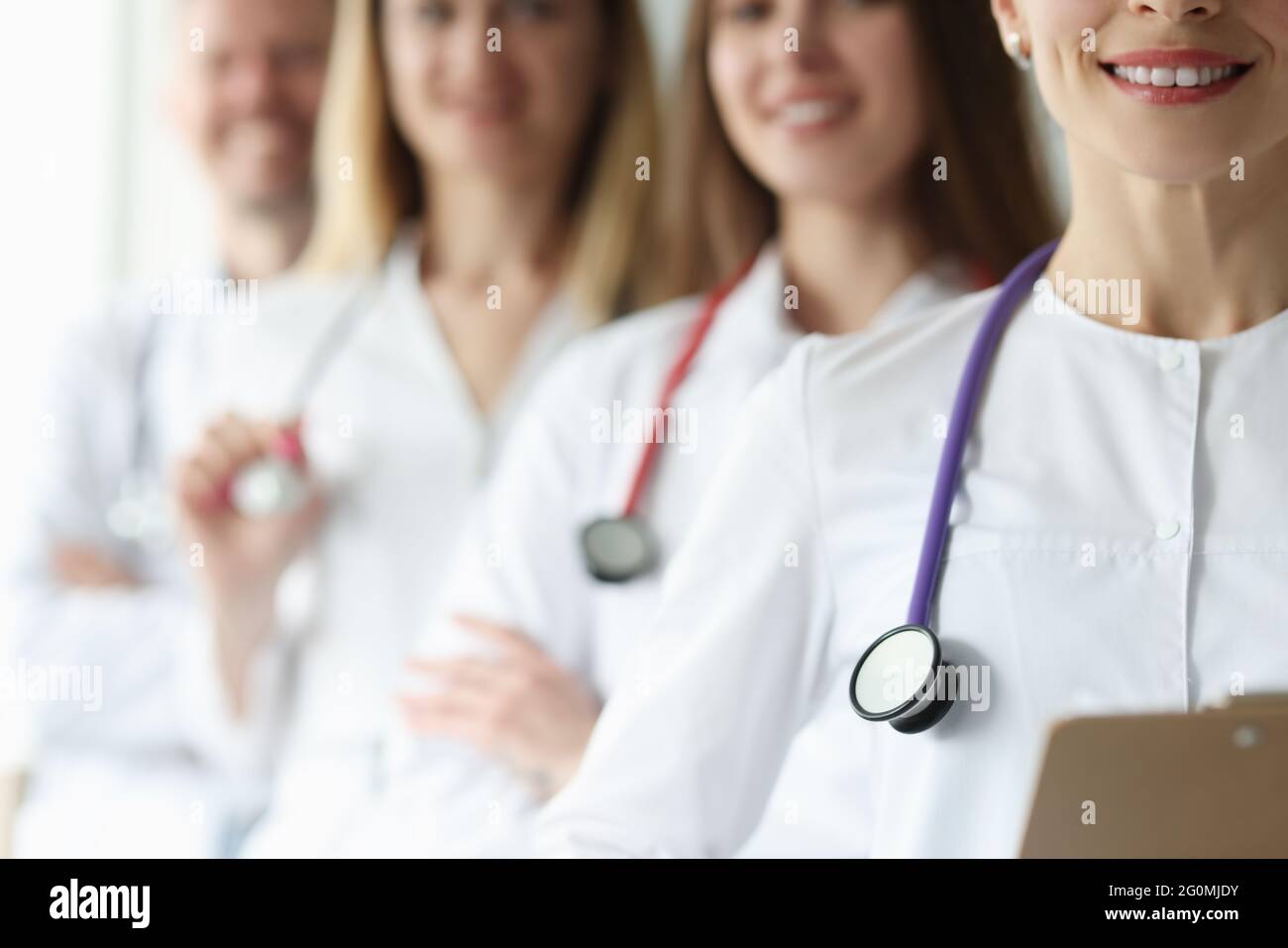 Team of doctor in white coats and stethoscopes stand together Stock Photo
