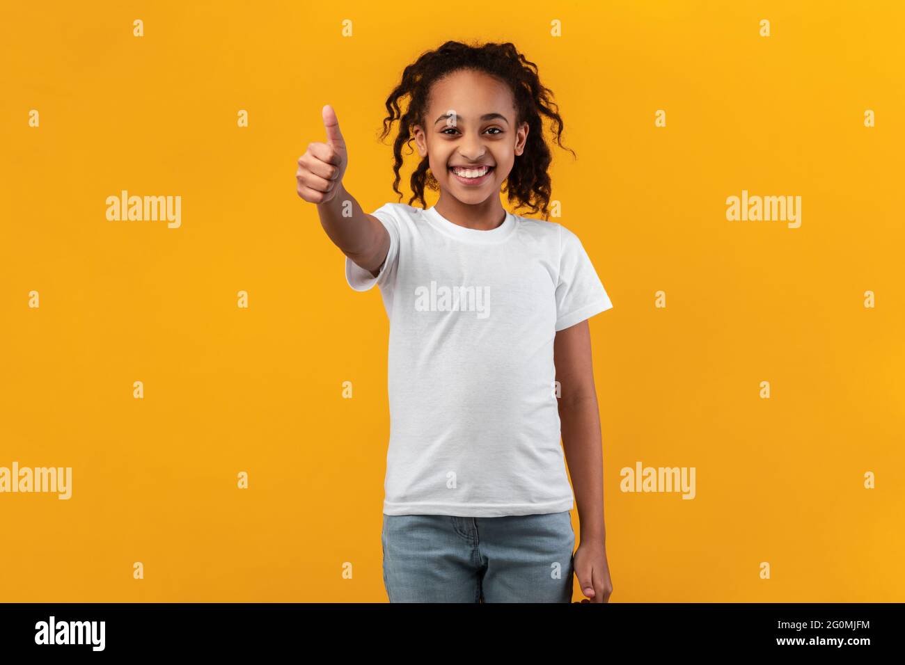 Happy black girl gesturing thumbs up and smiling Stock Photo - Alamy