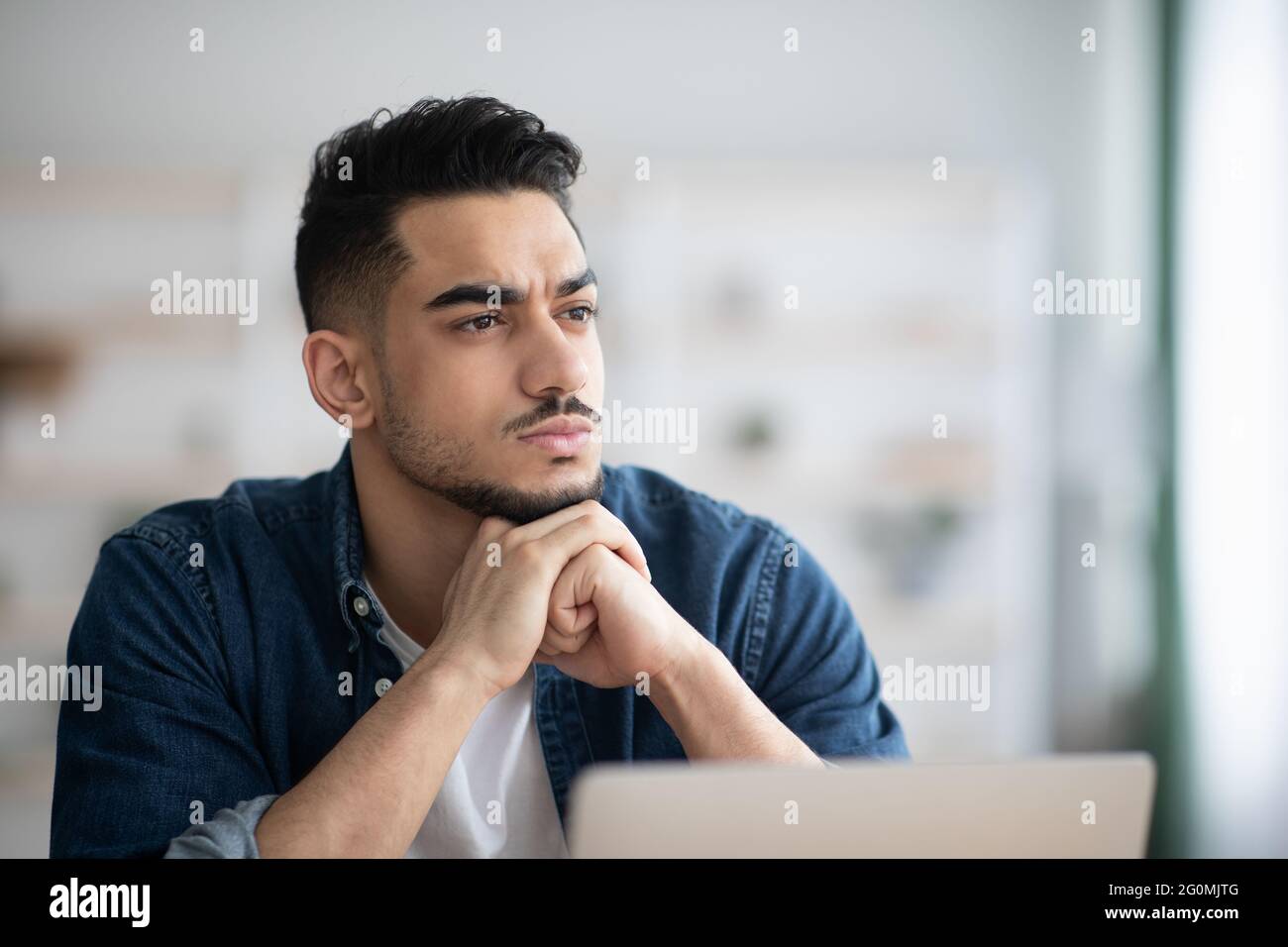 Thoughtful arab man employee working on laptop Stock Photo