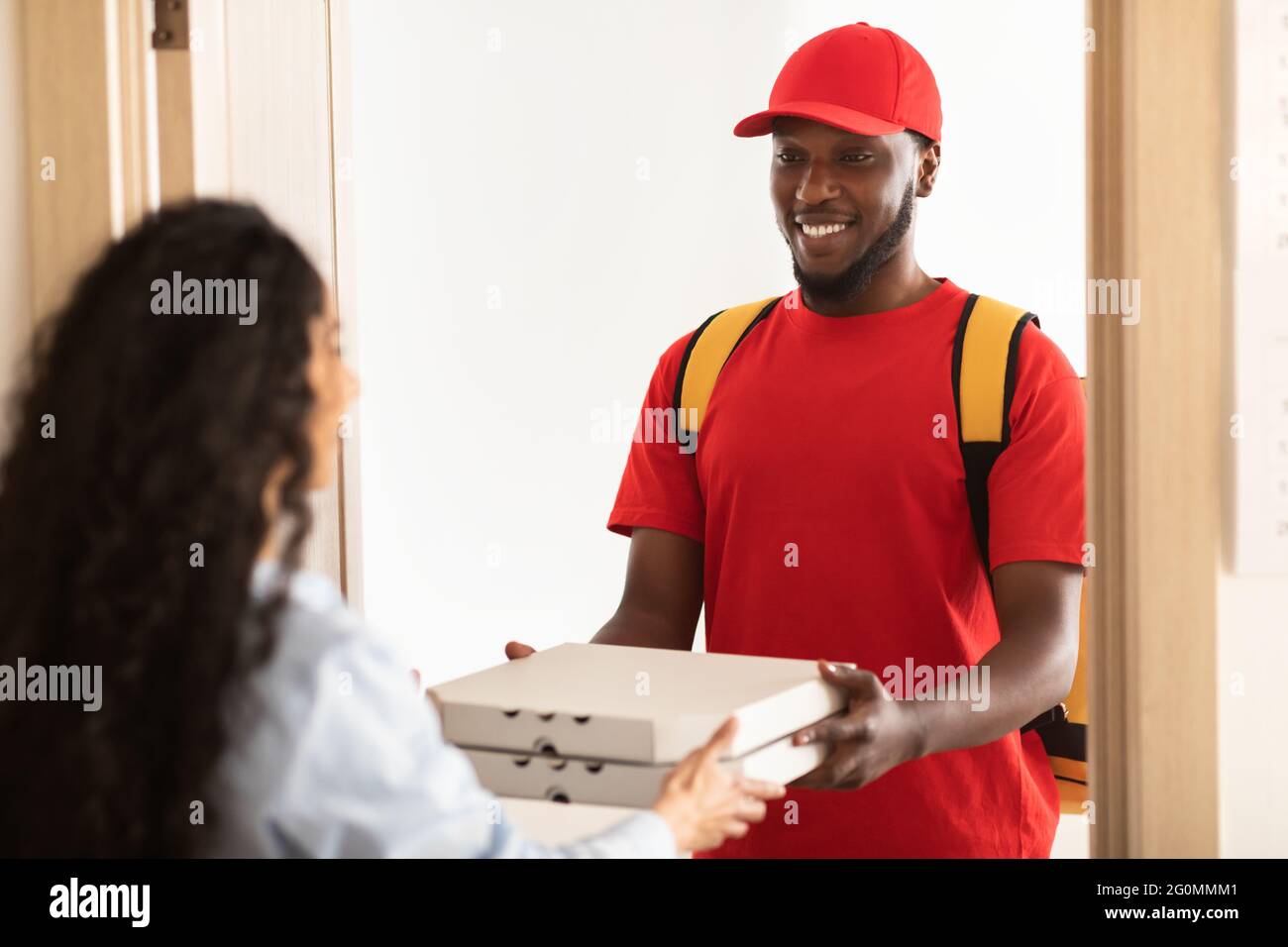 Black delivery man holding and giving pizza boxes Stock Photo