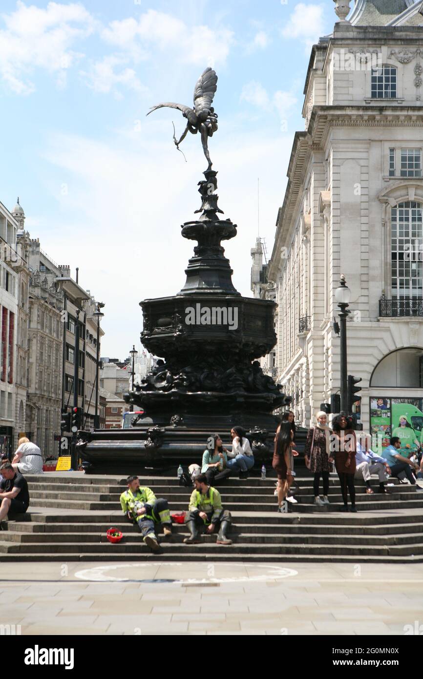 People enjoying the warm weather on the steps of Shaftesbury Memorial Fountain in Piccadilly Circus, London. The UK has recorded its third successive warmest day of the year with temperatures reaching 26.6C in parts of the country. Picture date: Wednesday June 2, 2021. Stock Photo