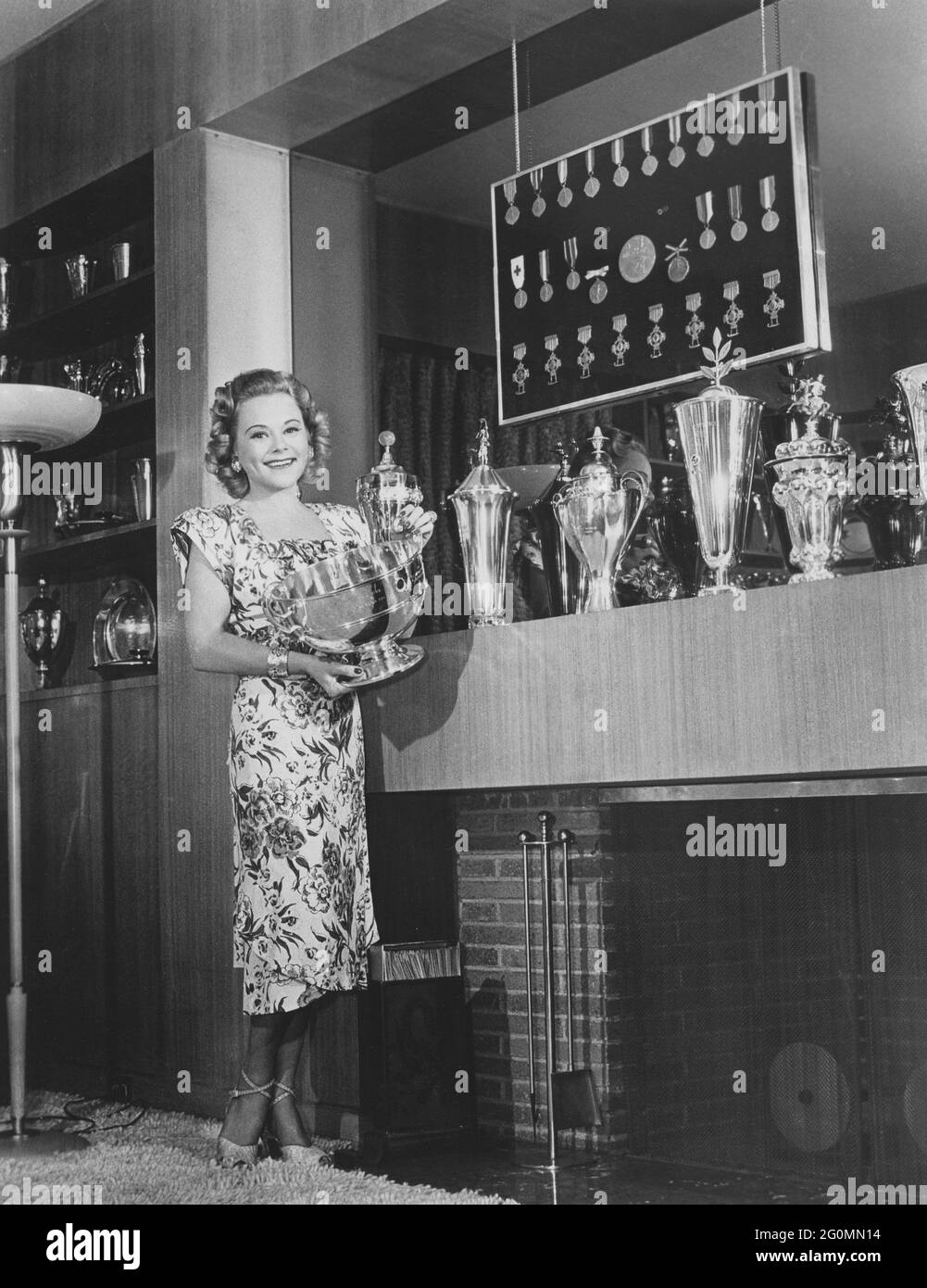 Sonja Henie. Norwegian figure skating champion, born april 8 dead october 12 1969. Pictured in her Hollywood home with parts of her trophy collection. Medals and silver trophys fills the wall and on the shelves. 1940s. Stock Photo