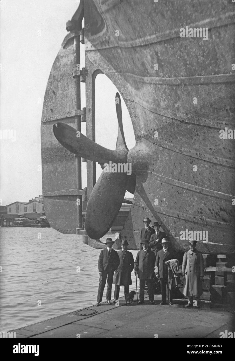 Dockyard in the 1920s. A ship is undergoing maintance and the ship is risen in a dry dock. One of the stern the propeller is visible and a it's size can be measured by comparing it to the people standing below it. Picture taken at Götaverken shipyard in Gothenburg Sweden in the 1920s. Stock Photo