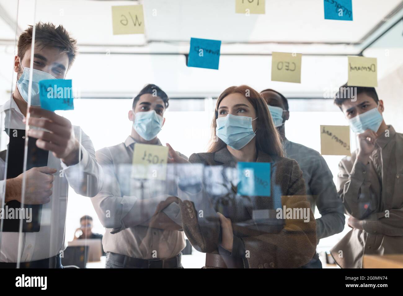 Colleagues in masks having meeting using sticky notes Stock Photo